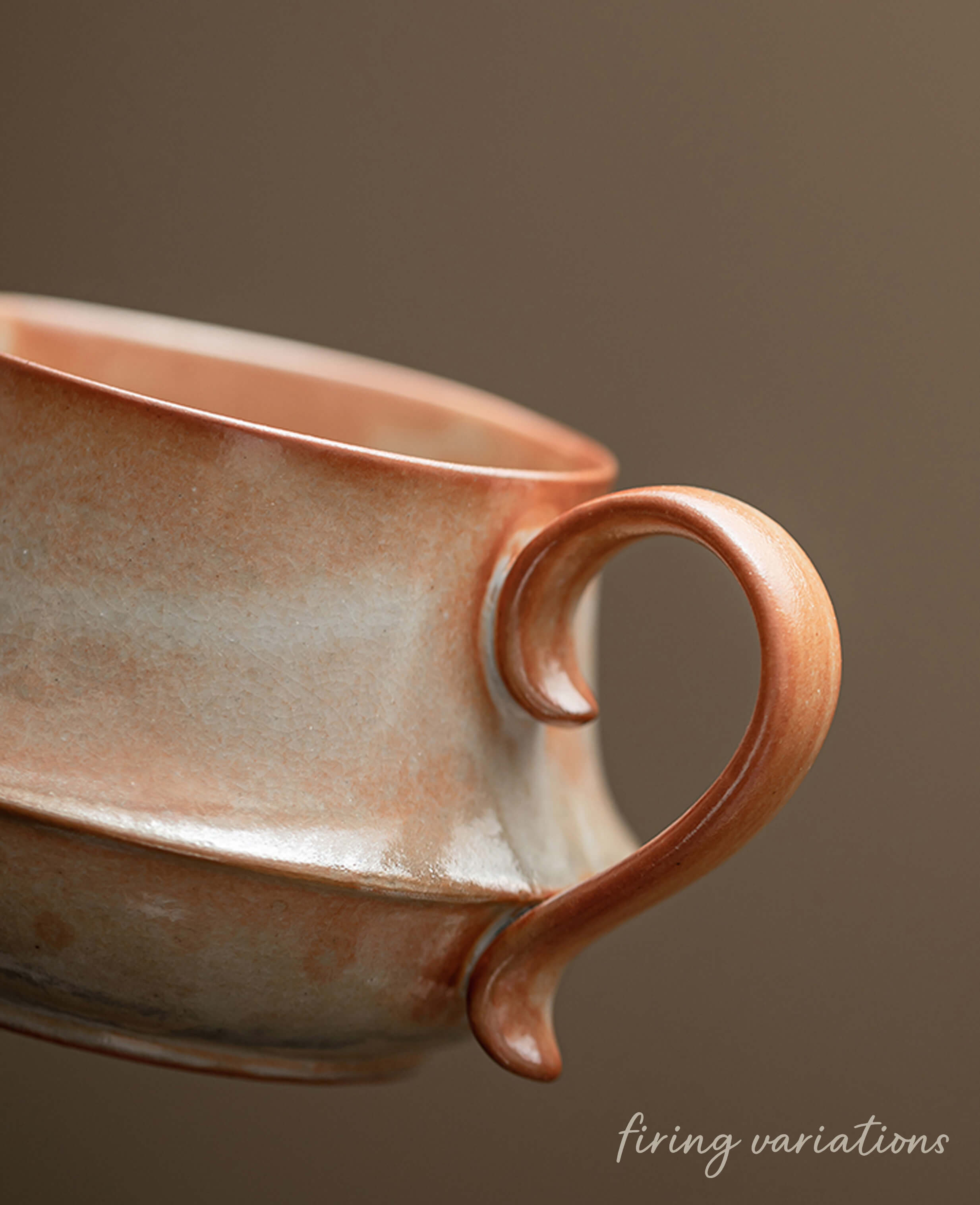 close up of handcrafted claybourne ceramic coffee and tea cup handle showing warm terracotta glaze and unique firing variations artisan stoneware
