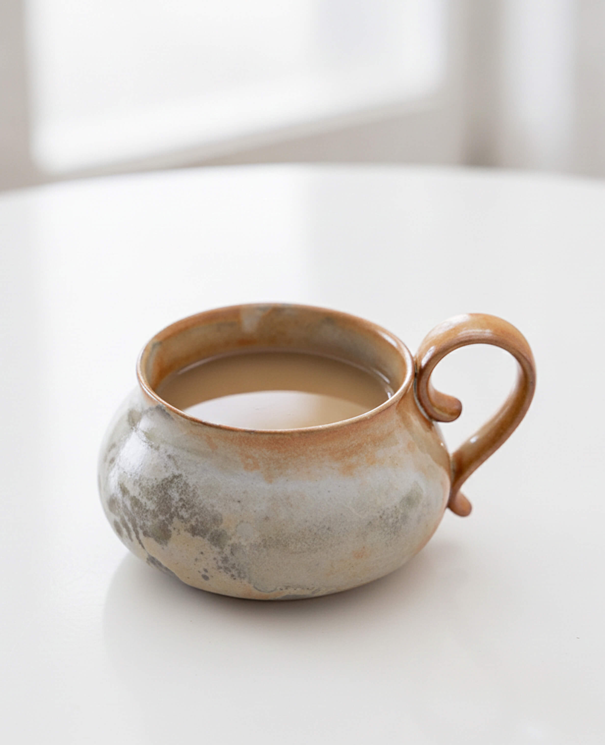 cloudstone handmade ceramic mug filled with coffee showcasing rustic glaze and curved form