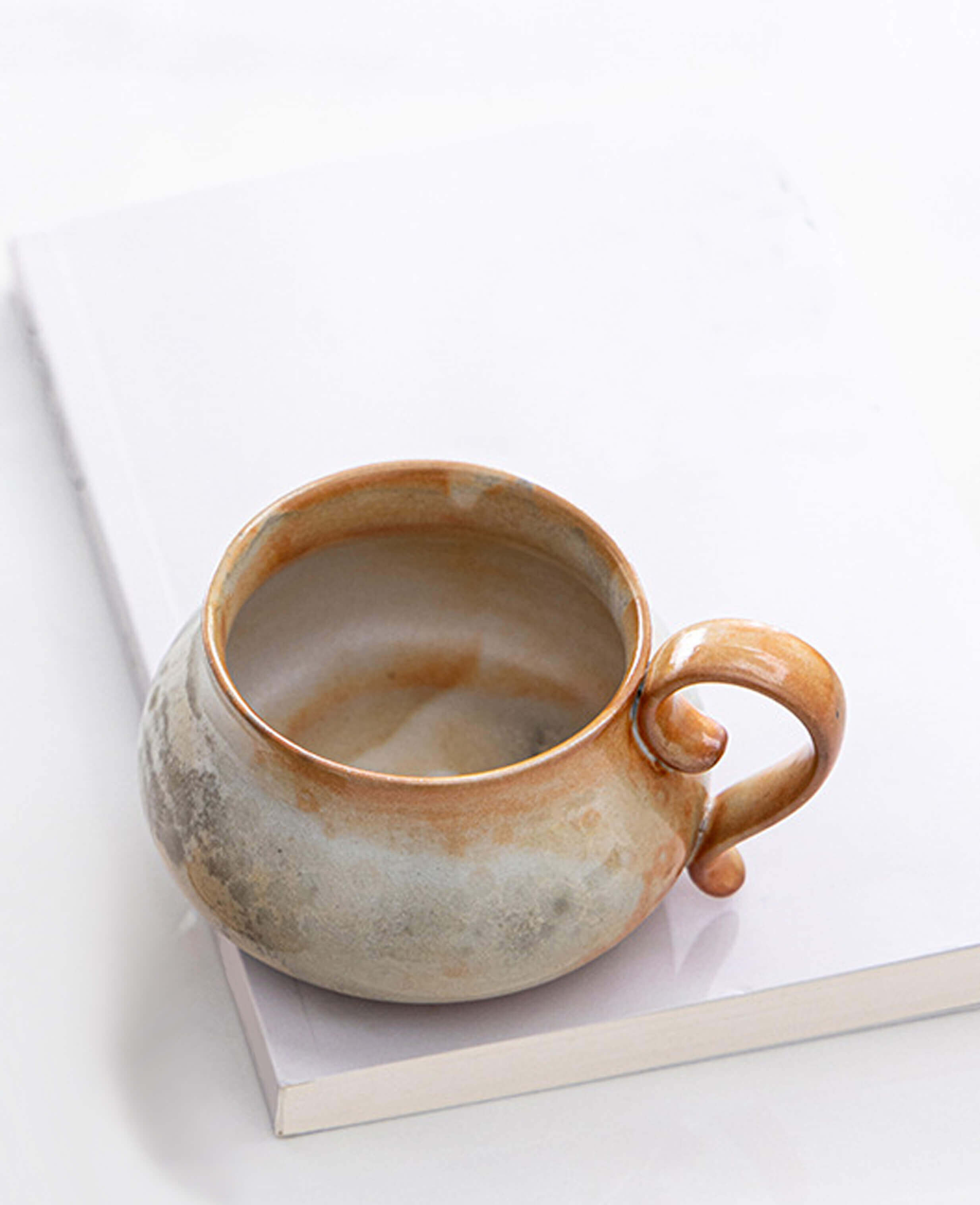 cloudstone artisan pottery mug with organic glaze sitting on a notebook bright and airy setting