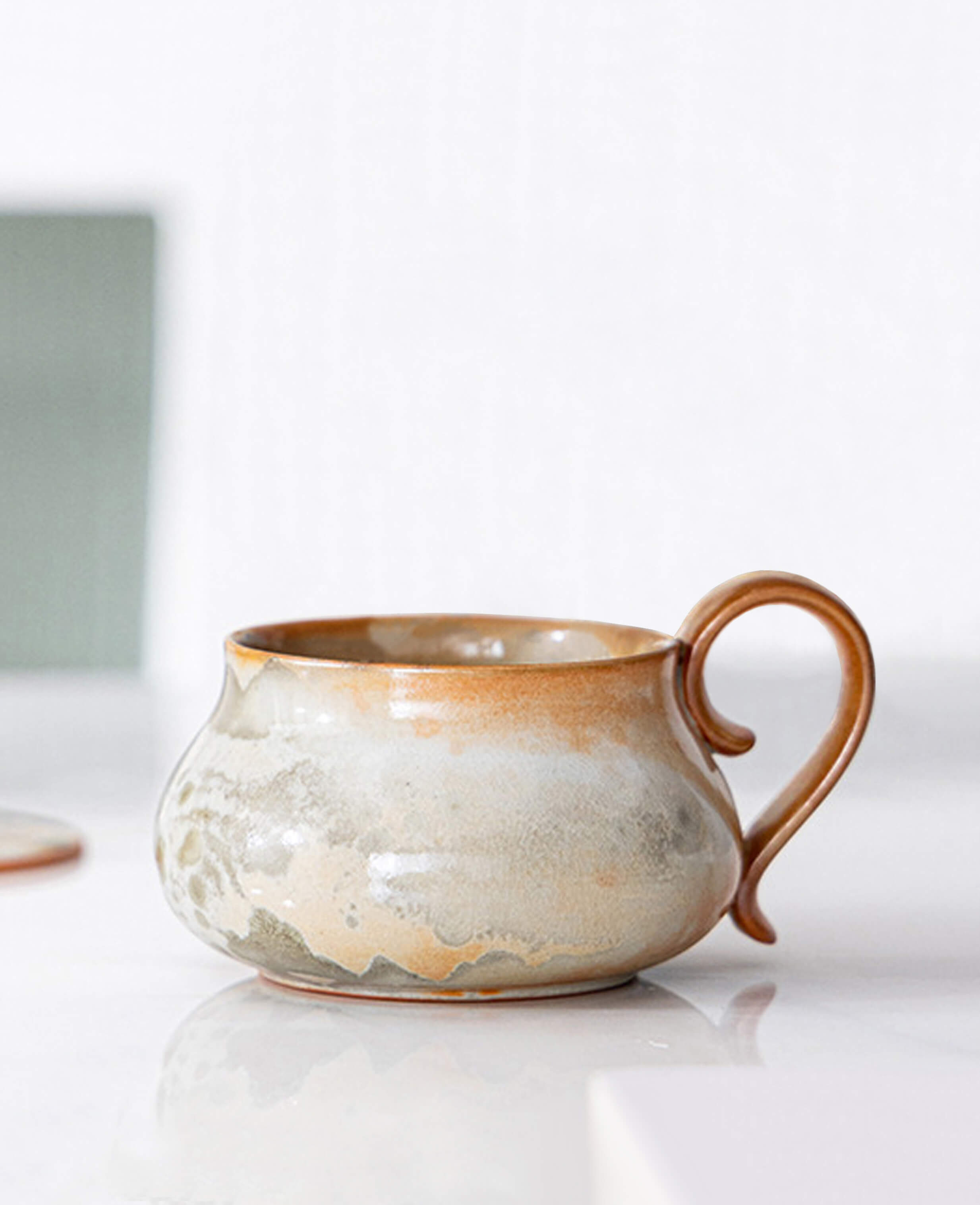handmade cloudstone ceramic coffee and tea mug with earthy glaze resting on white table