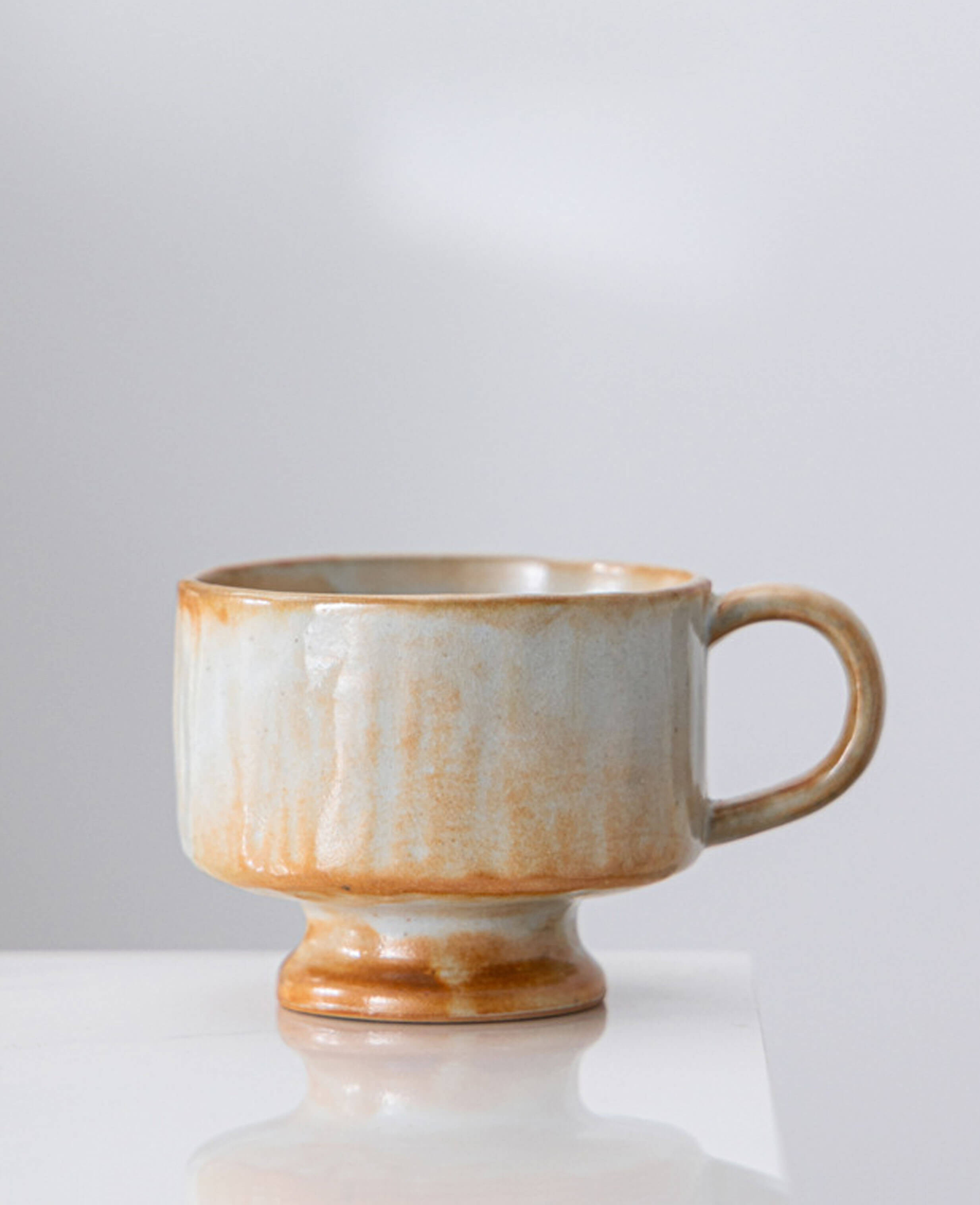 dawn chalice handcrafted ceramic coffee and tea cup with pedestal base and warm terracotta and cream glaze artisan stoneware design