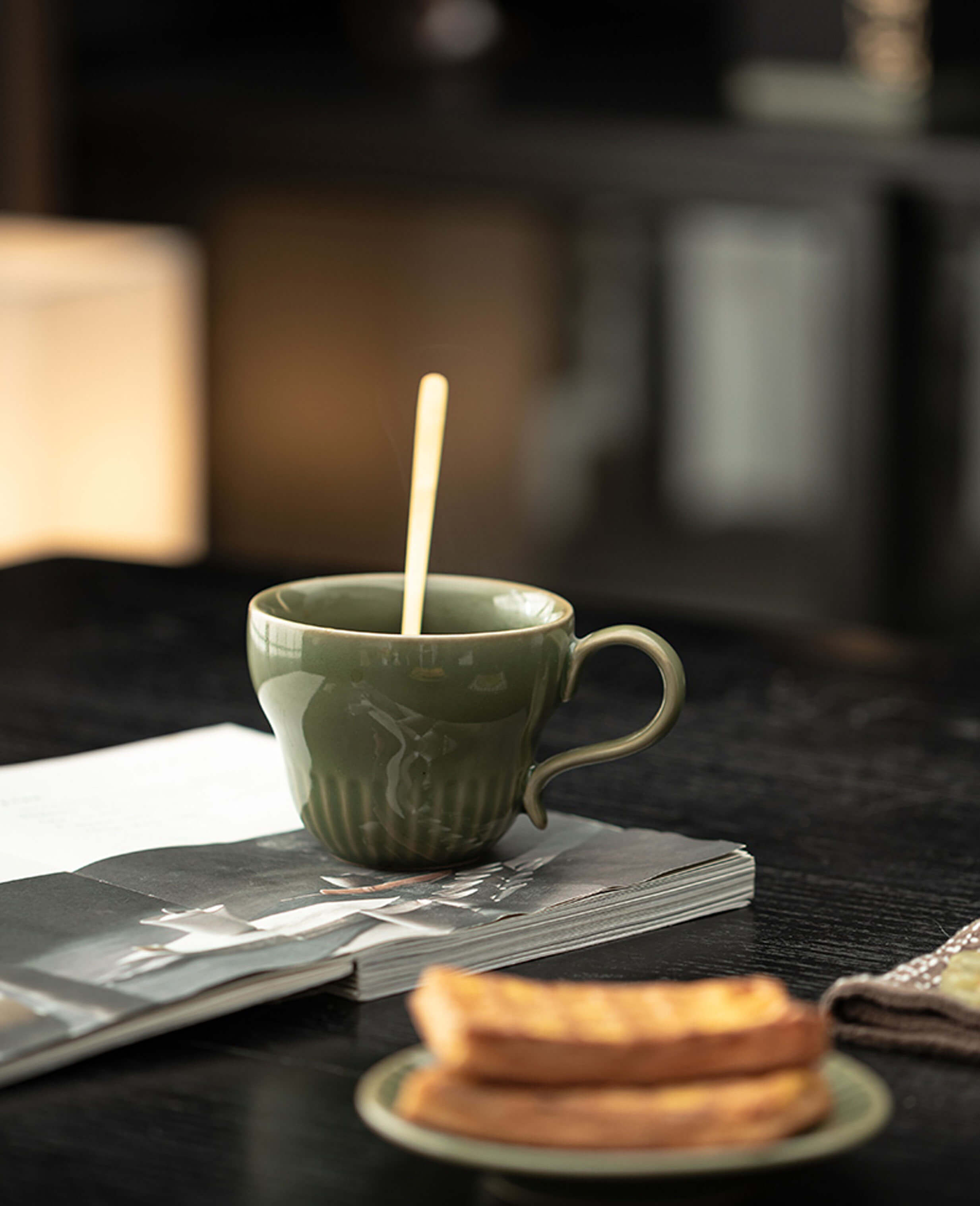 greenstill crest porcelain coffee cup in morning light with toast and open magazine