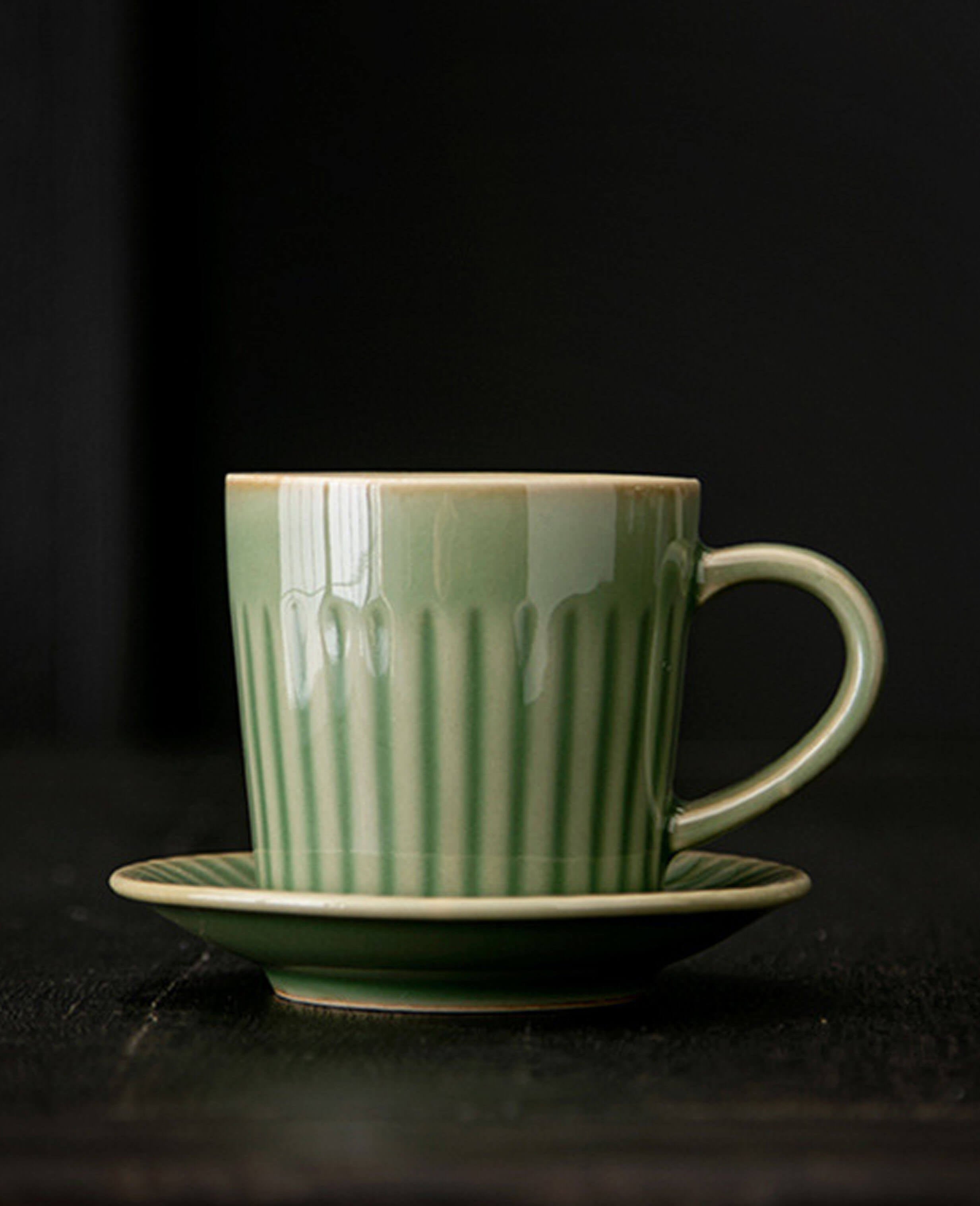 greenstill whisper fluted porcelain coffee cup with saucer against dark textured background