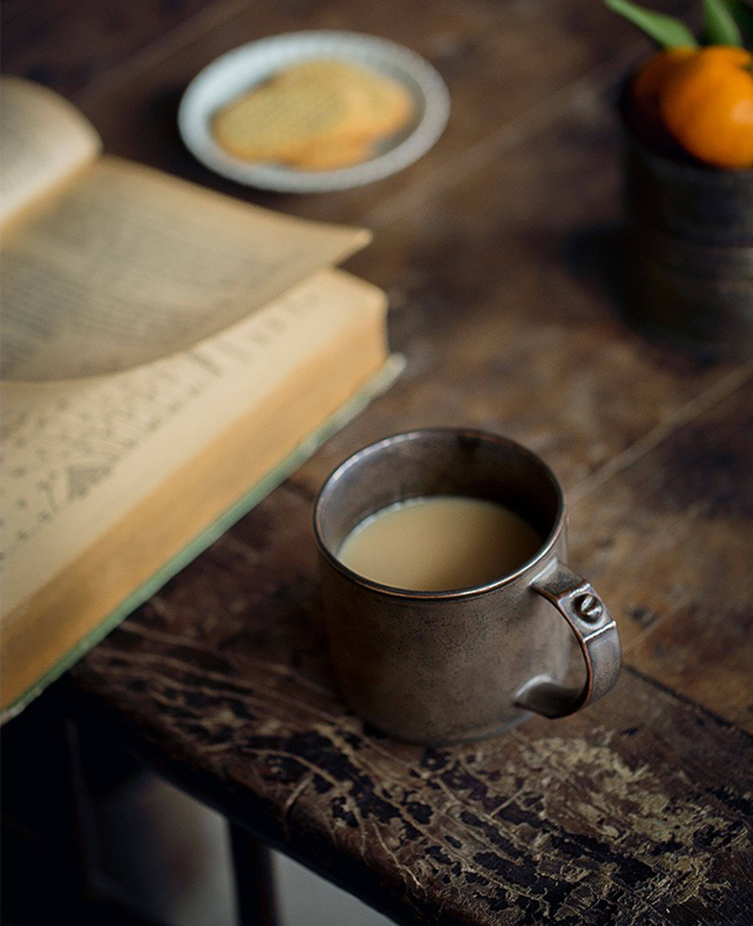 industrial ceramic coffee mug with milk, book and snacks in cozy setting