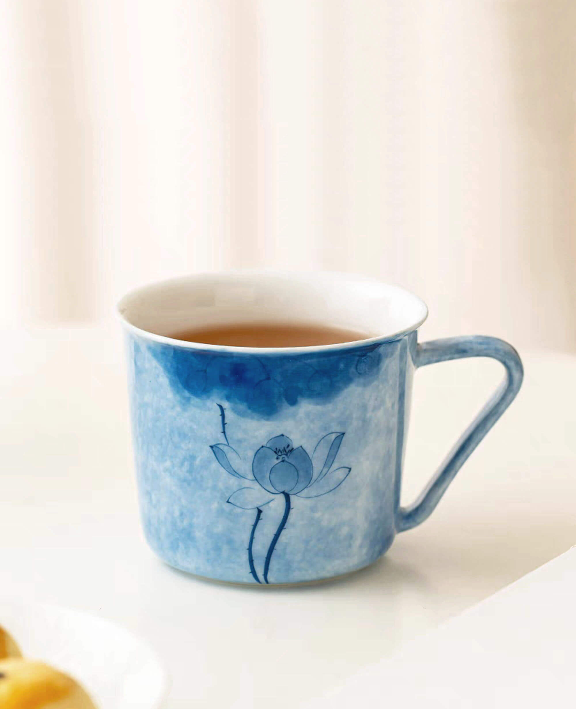 hand painted porcelain coffee and tea cup with blue lotus design on white table from the inked drizzle diary collection