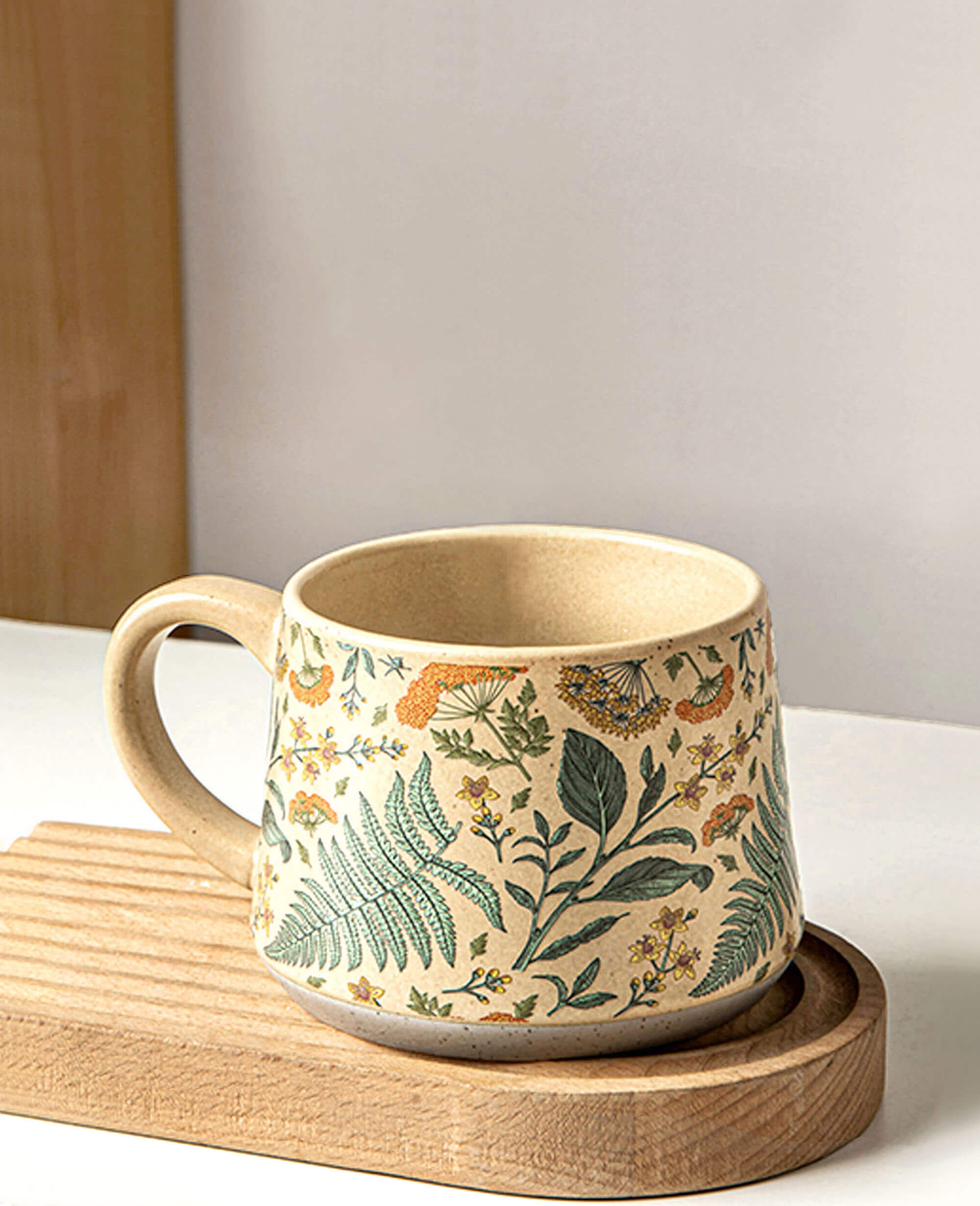 july note stoneware floral mug on a wooden coaster captured in warm daylight against a minimalist background