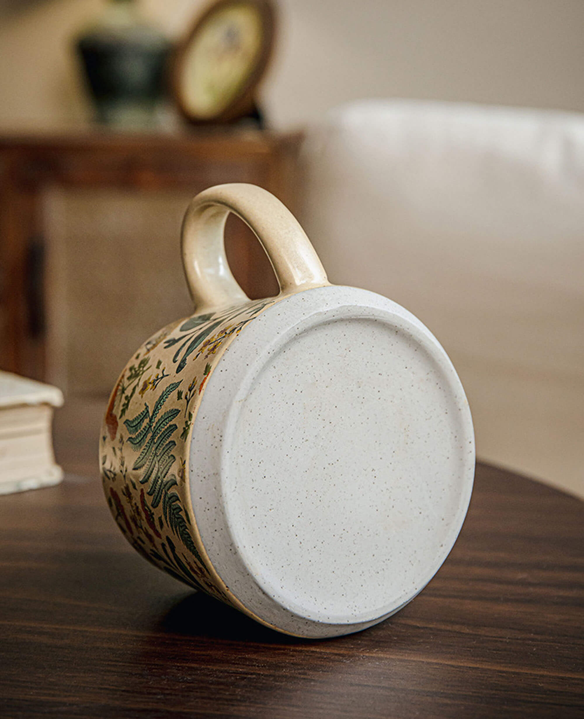 underside of july note stoneware coffee mug showing unglazed base and handle curve against a wooden tabletop