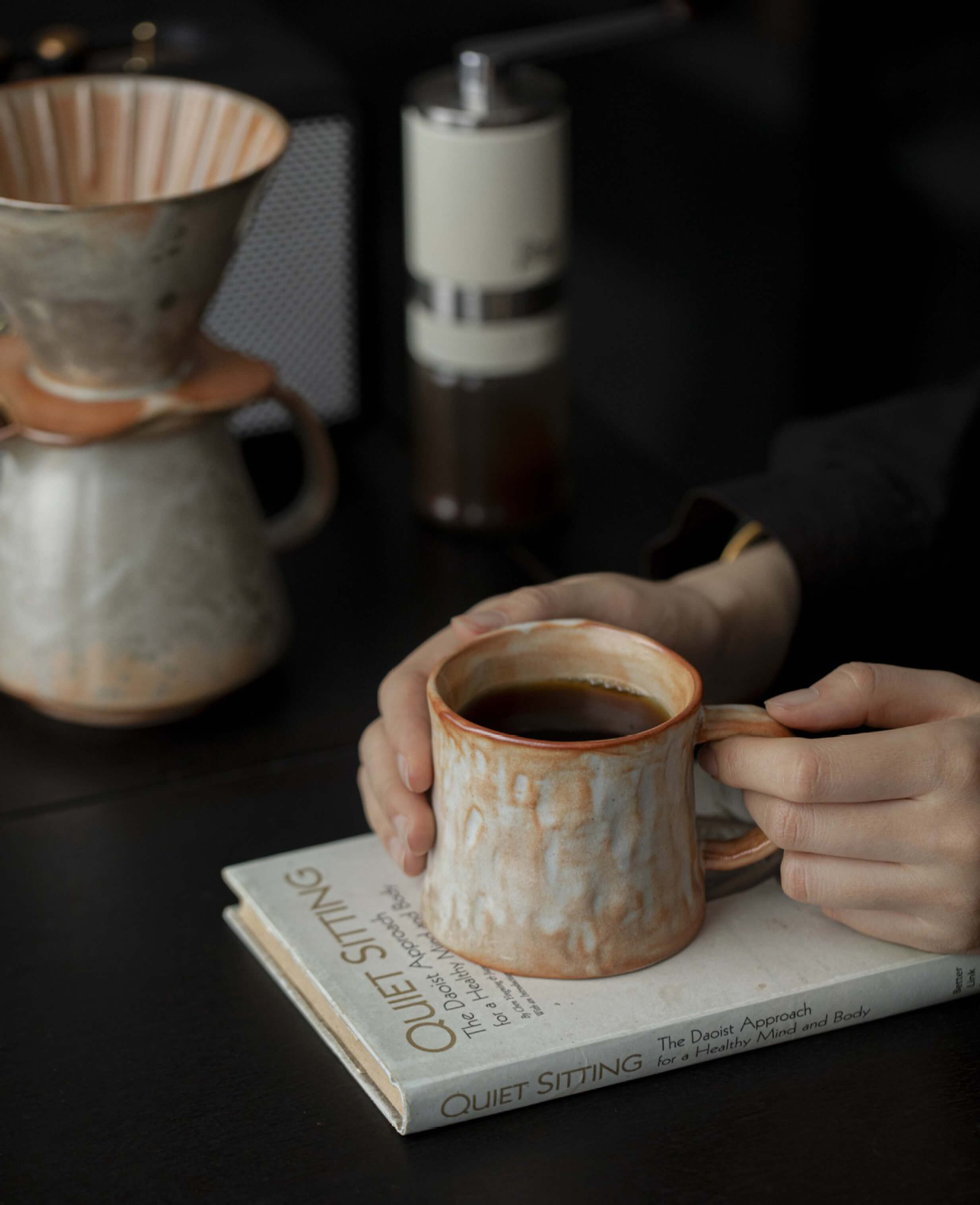 artisan mistburn ceramic coffee mug with earthy terracotta glaze and soft ash like finish from kiln firing held in hands