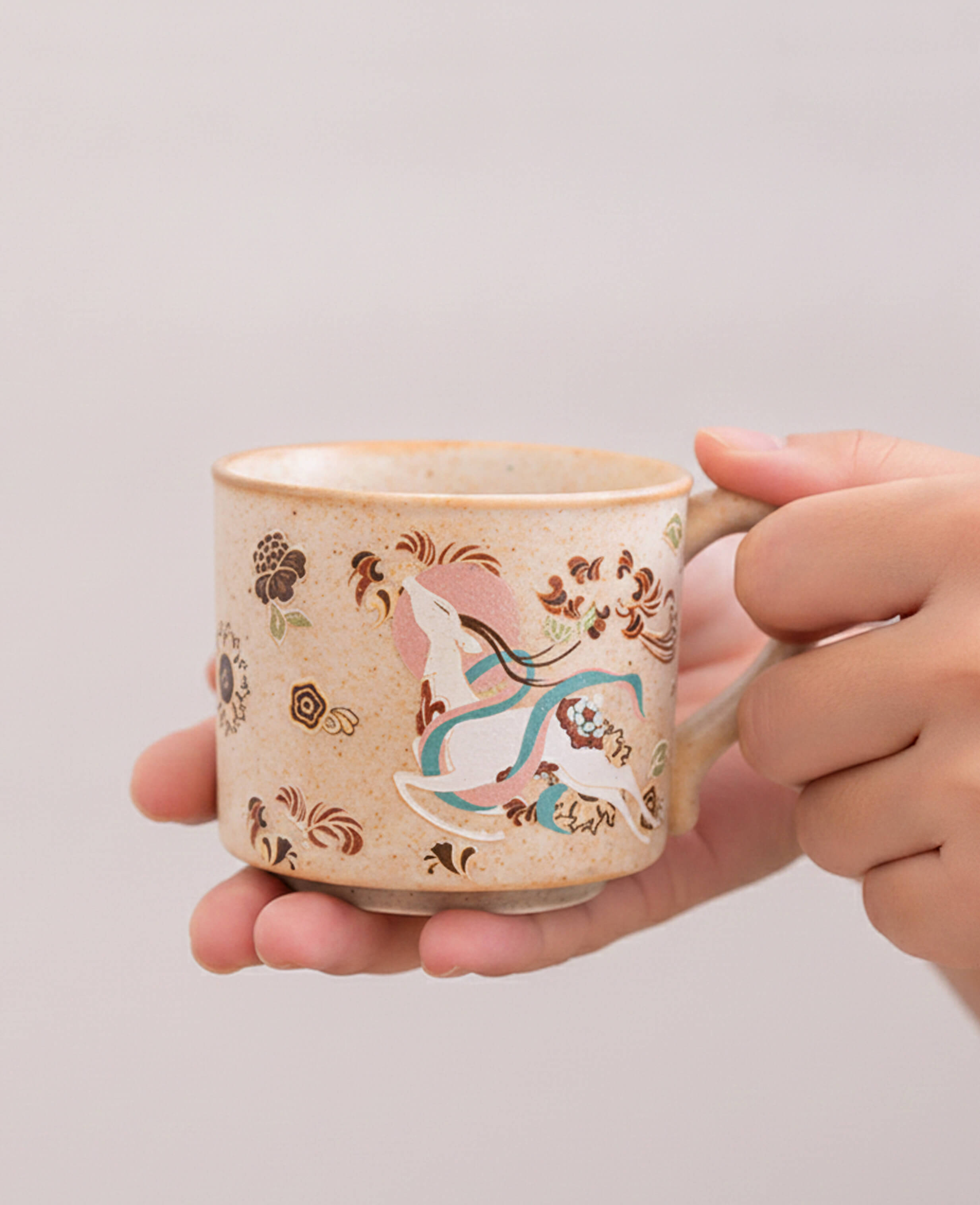 handcrafted beige ceramic cup held in hands with artisanal design inspired by dunhuang art