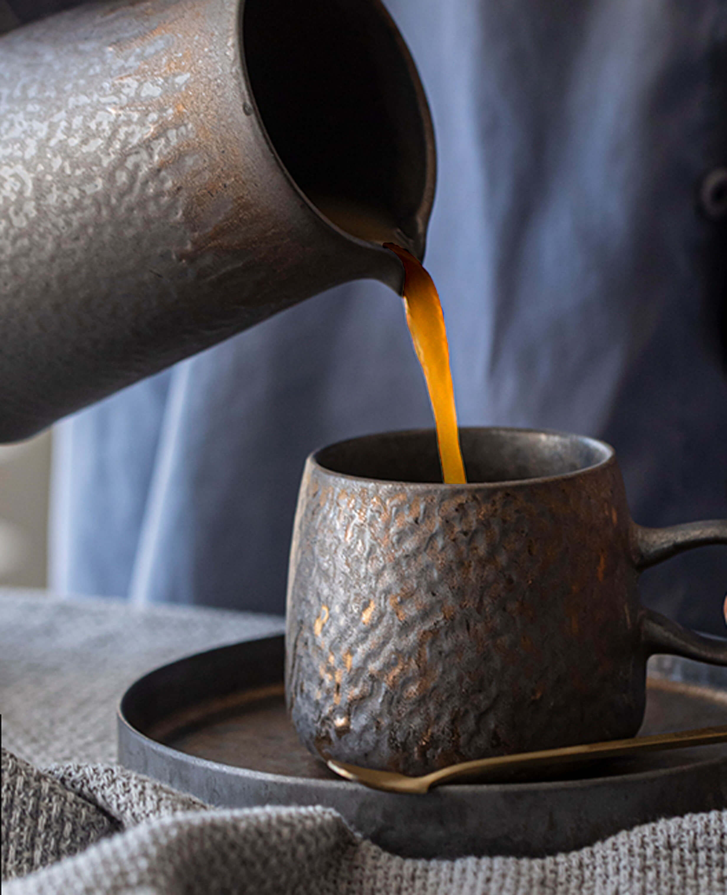 a mid-pour moment as coffee flows into the handcrafted ceramic rustglow lumen cup highlighting the cup’s ripple-textured body