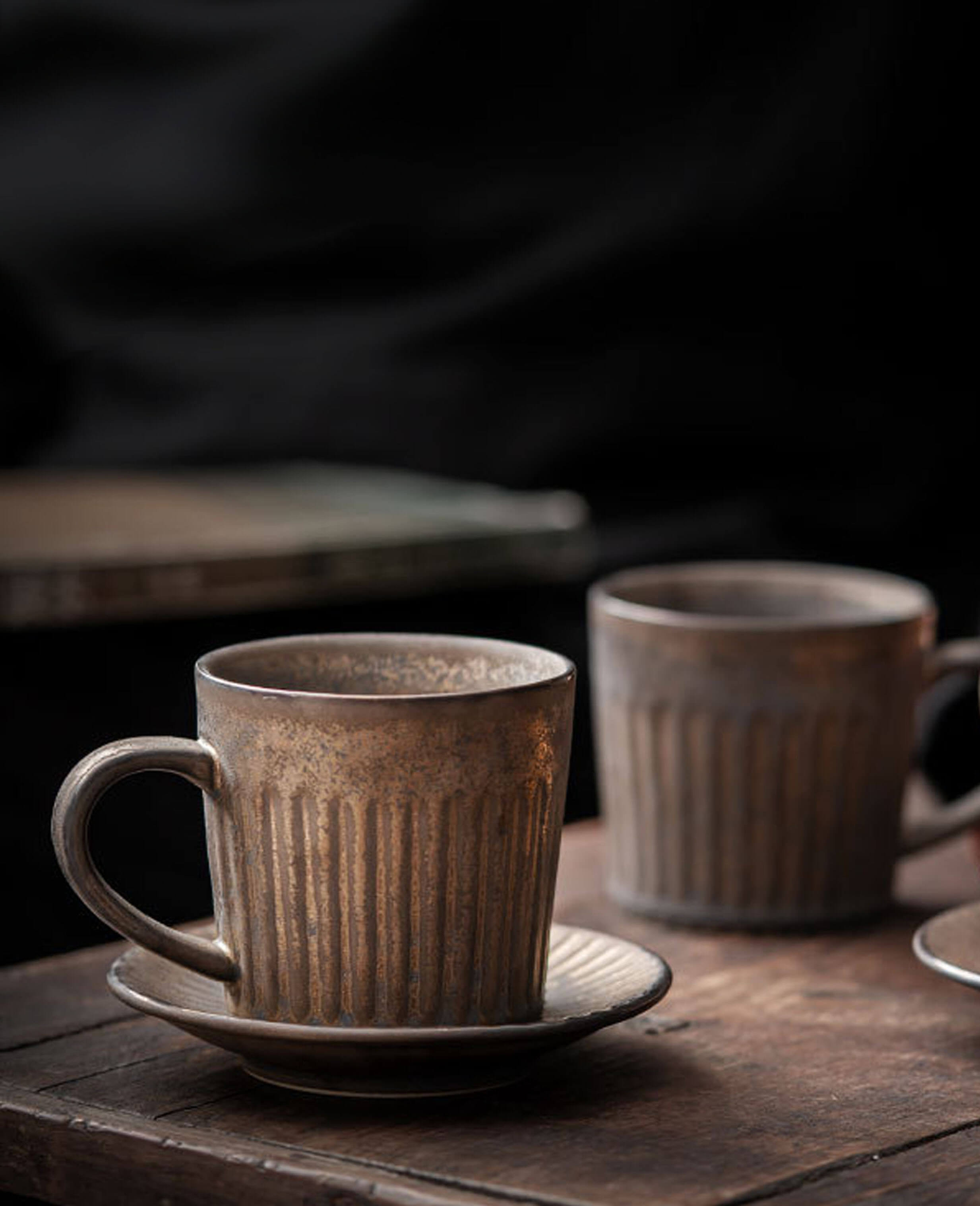 set of rustglow strata handcrafted ceramic coffee cups with a ridged rusty glaze texture on a wooden surface