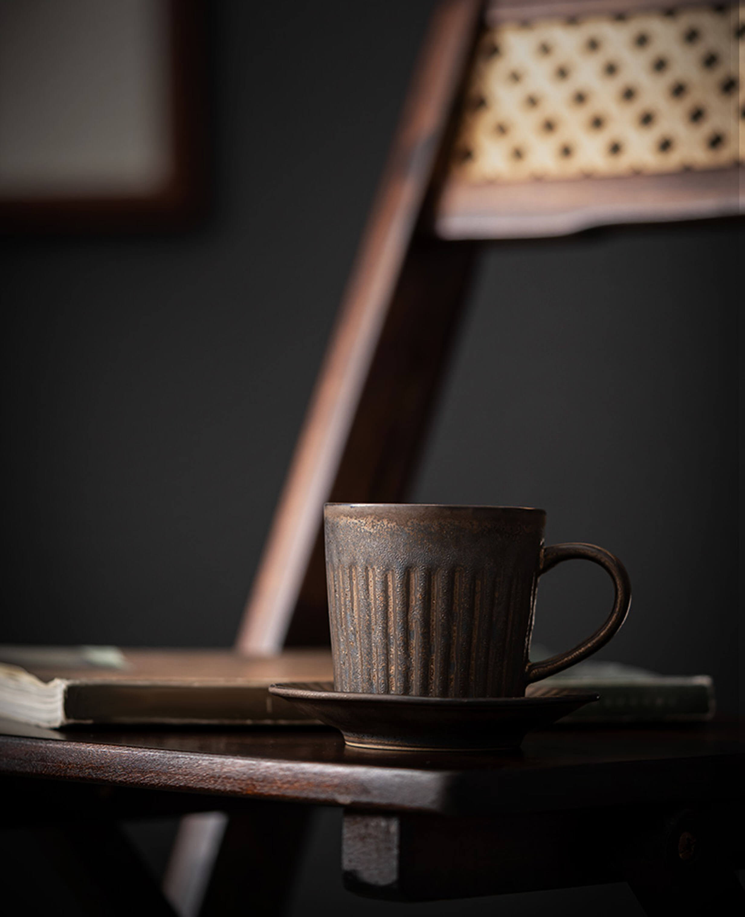 rustglow strata handcrafted stoneware coffee cup with a weathered rusty glaze sitting elegantly on a wooden chair