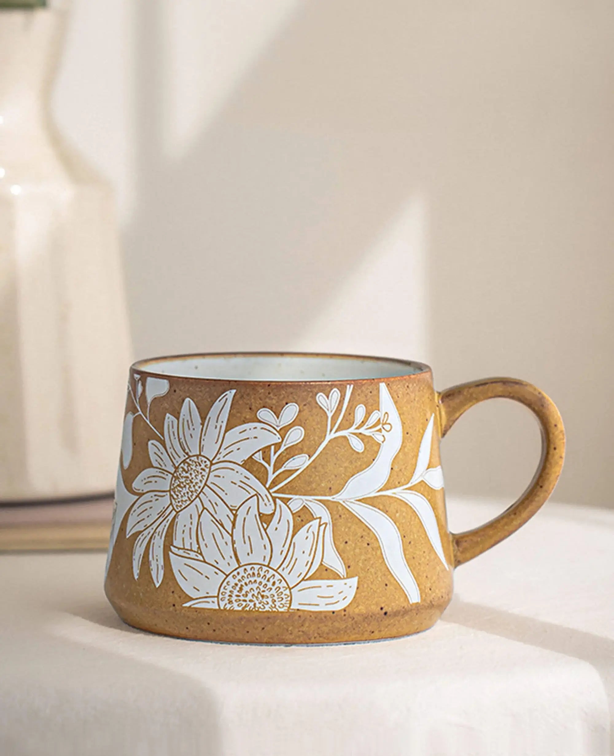 minimalist summer coffee mug with daisy outline pattern resting on soft neutral fabric surface