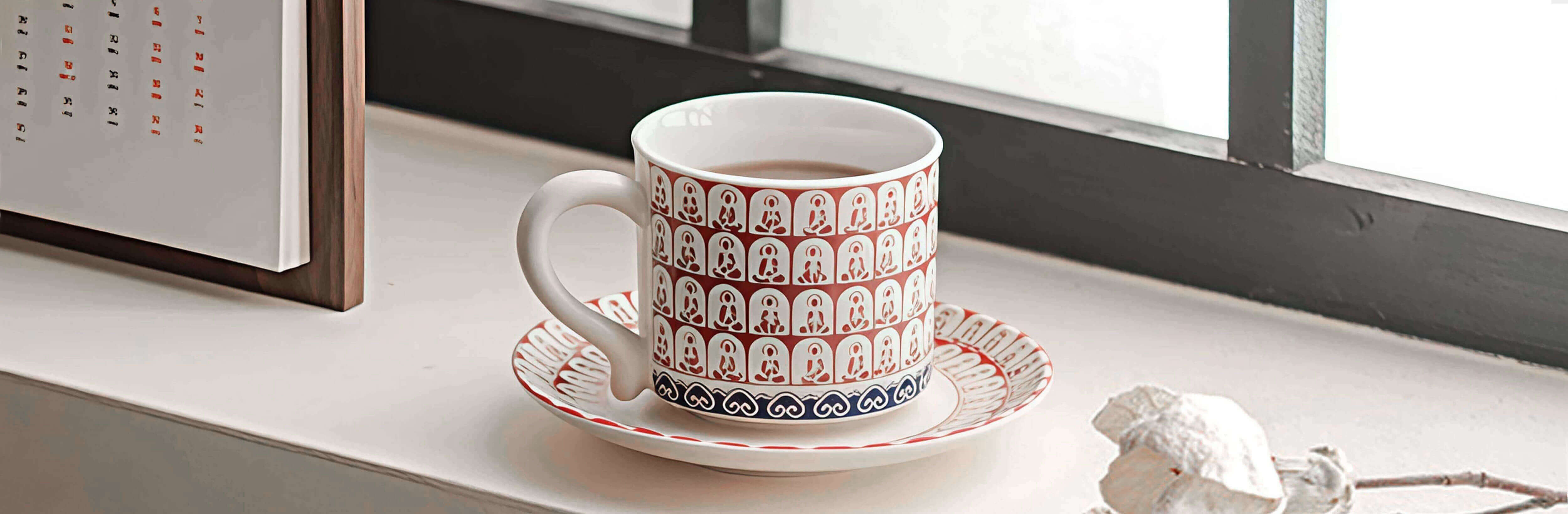 thousand buddhas crimson ceramic coffee and tea mug on windowsill with soft natural light hero banner image for ts & cs store