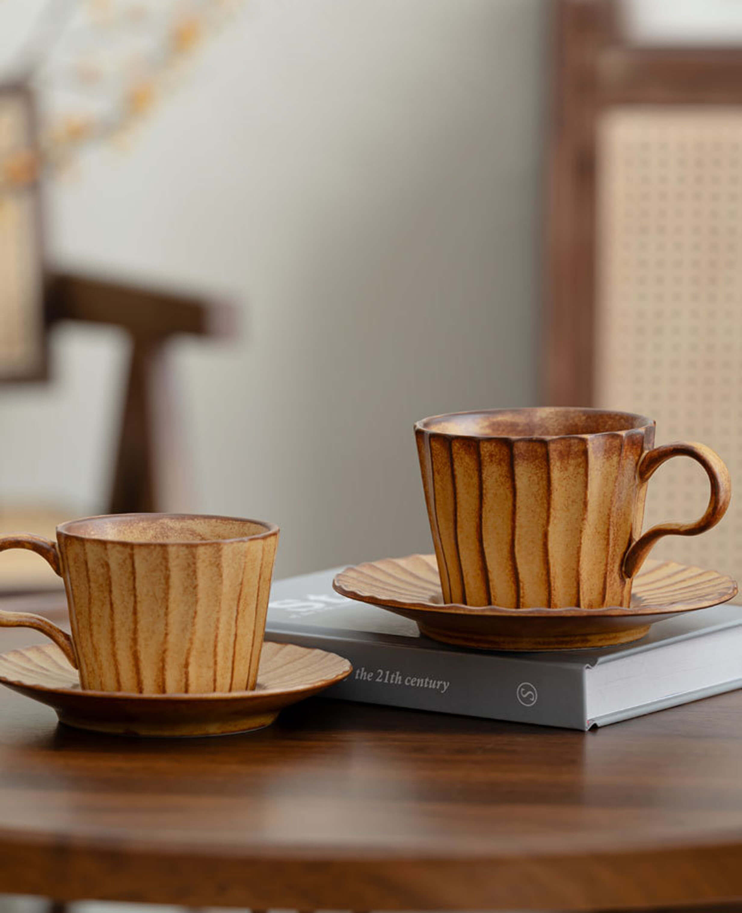 two toffee reverie flow coffee cups with saucers displayed on a book