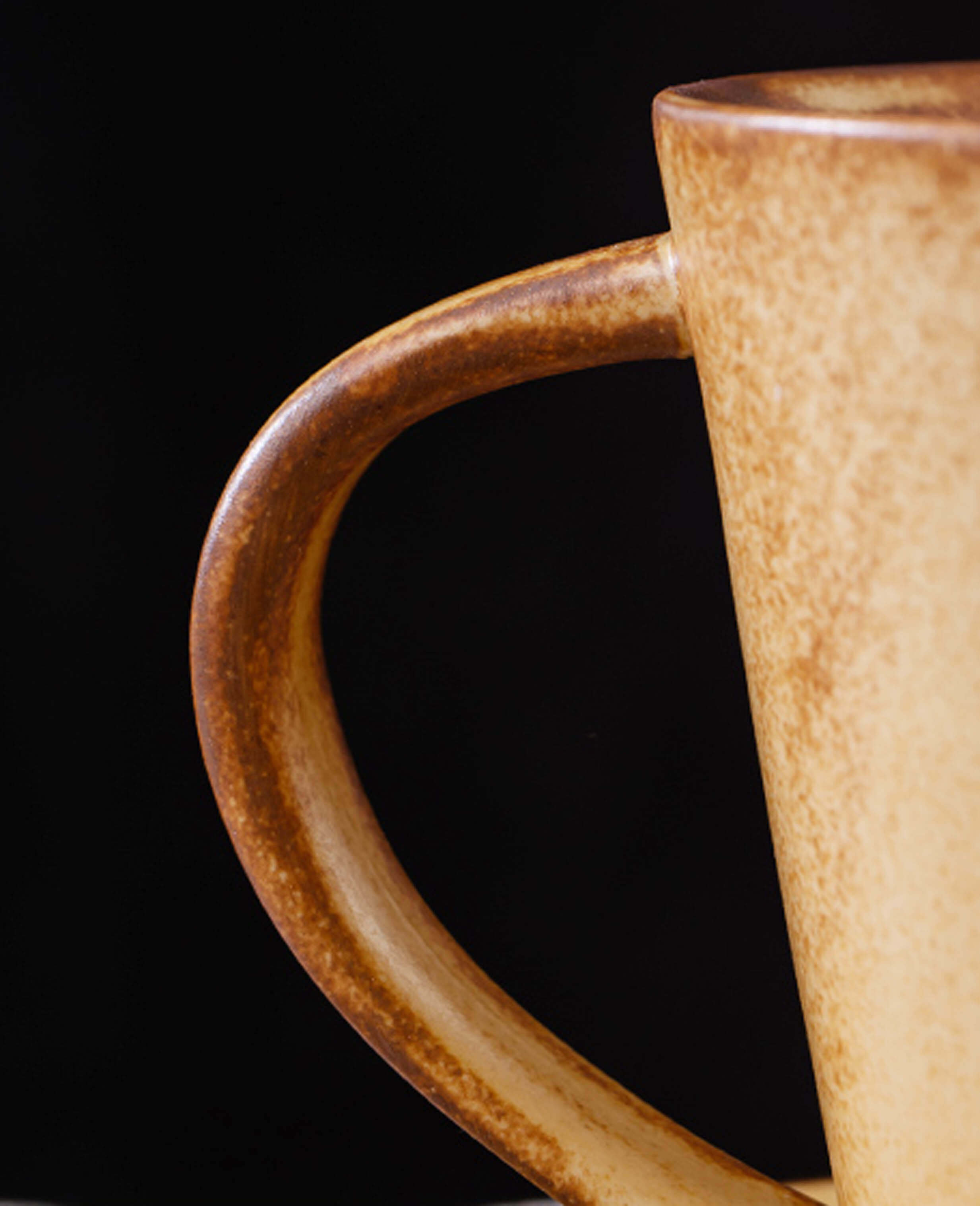 detail of curved ceramic toffee reverie thalen coffee mug handle with rustic toffee glaze finish