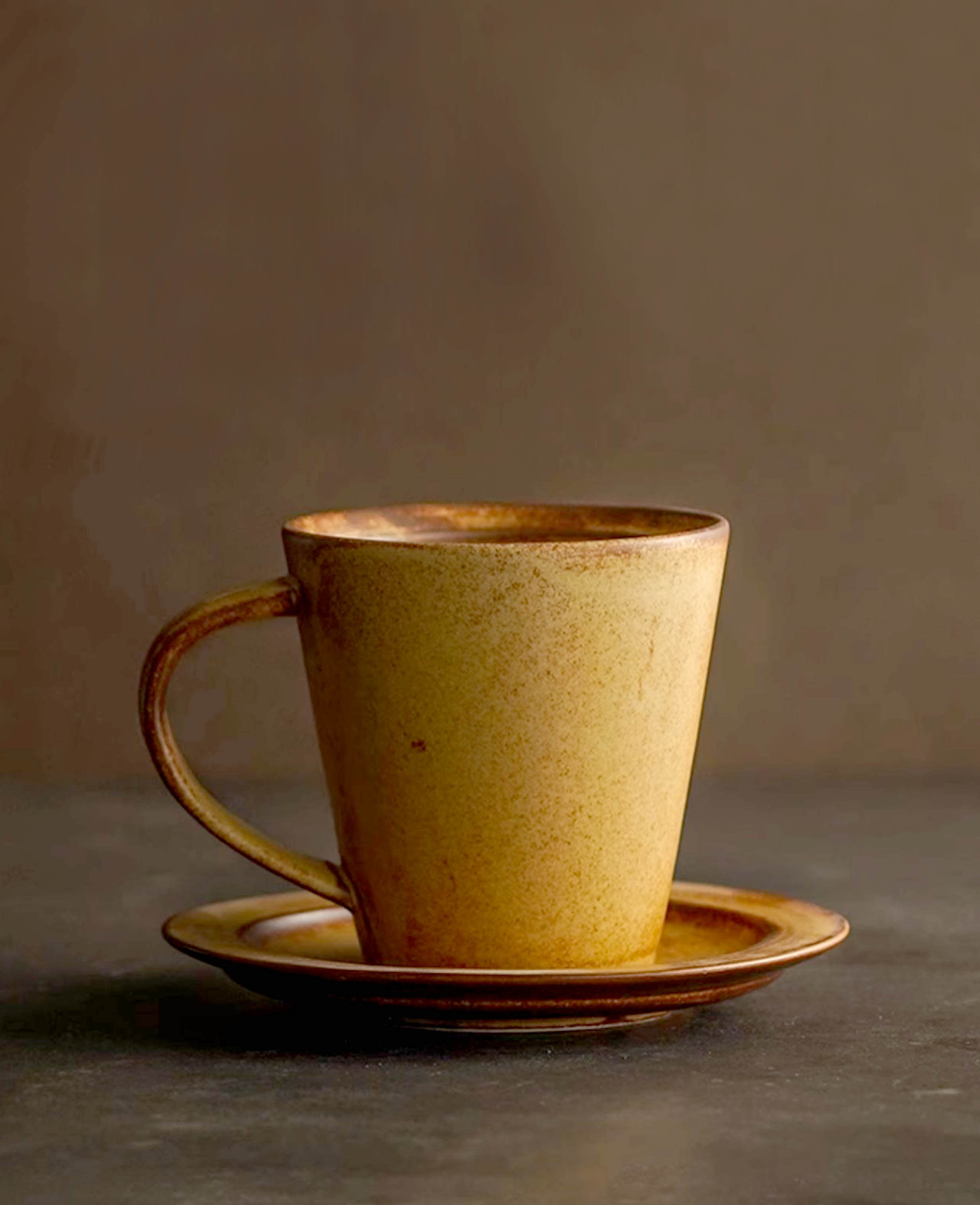 toffee reverie thalen handcrafted ceramic coffee mug and saucer set styled on stone grey surface