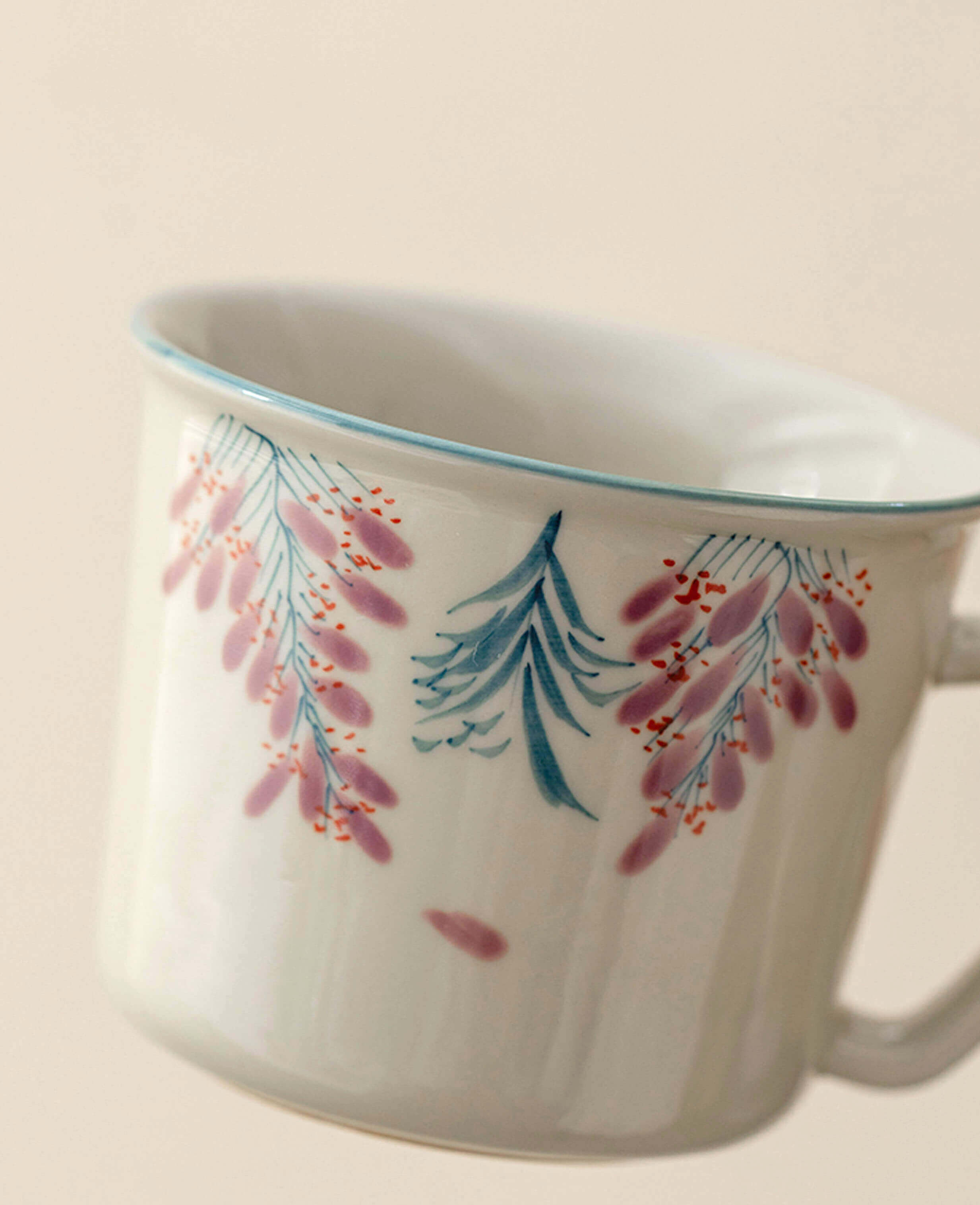 close up of wisteria trace hand painted porcelain tea cup showing purple floral brushwork and blue rim detail