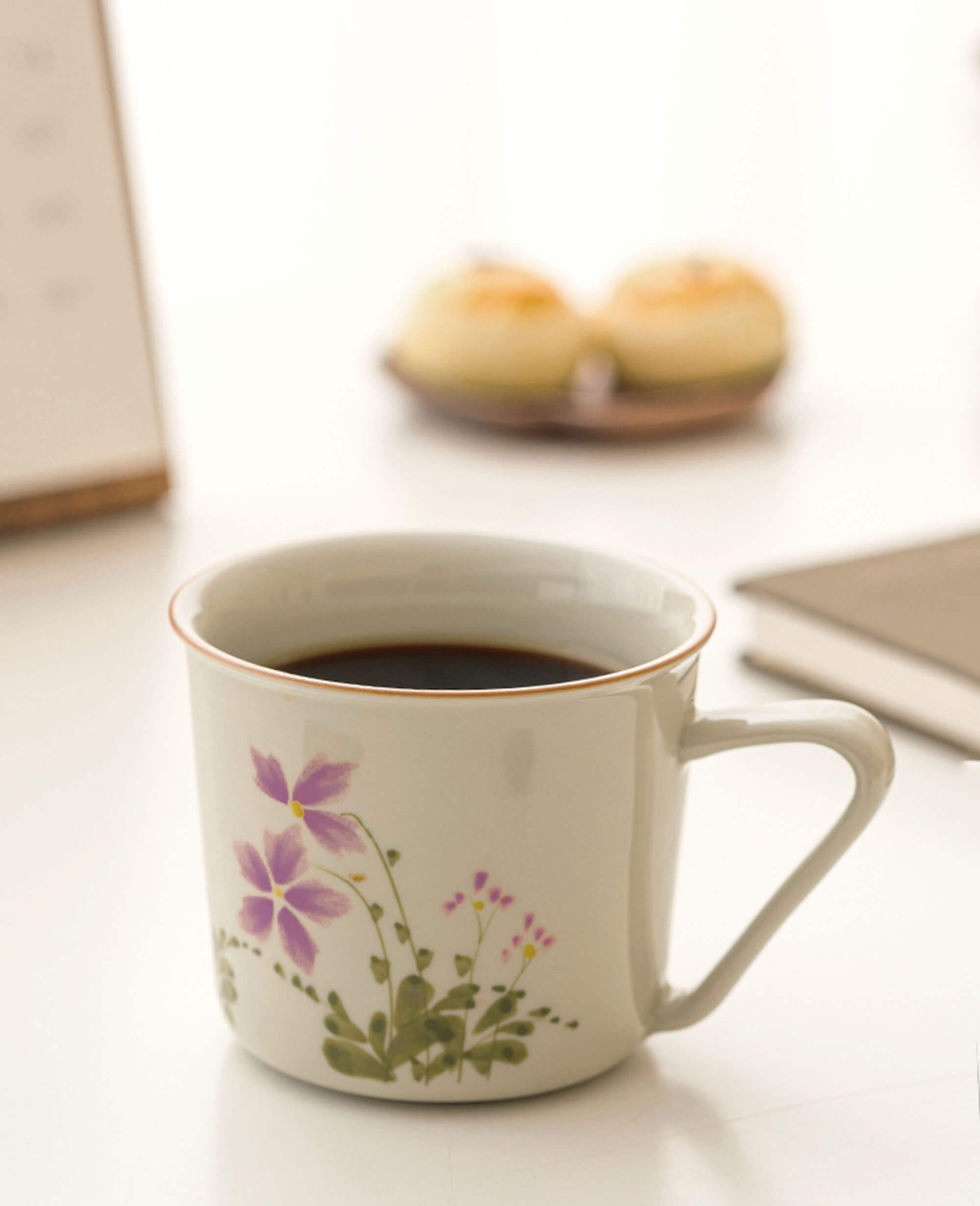 porcelain coffee cup with spring floral painting april verse design from the painted diary series softly lit near desserts