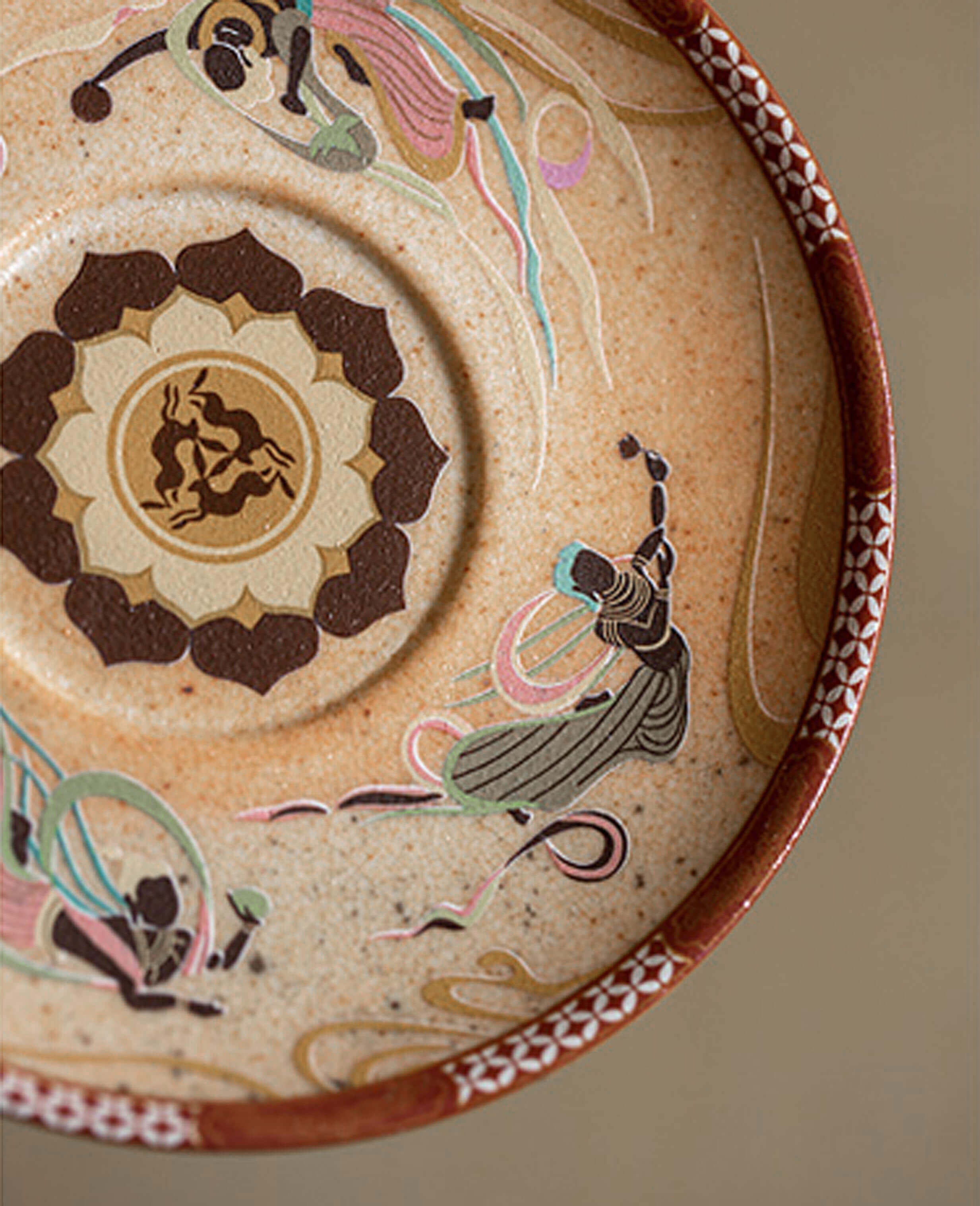 detailed close-up of saucer with painted apsaras and lotus mandala pattern