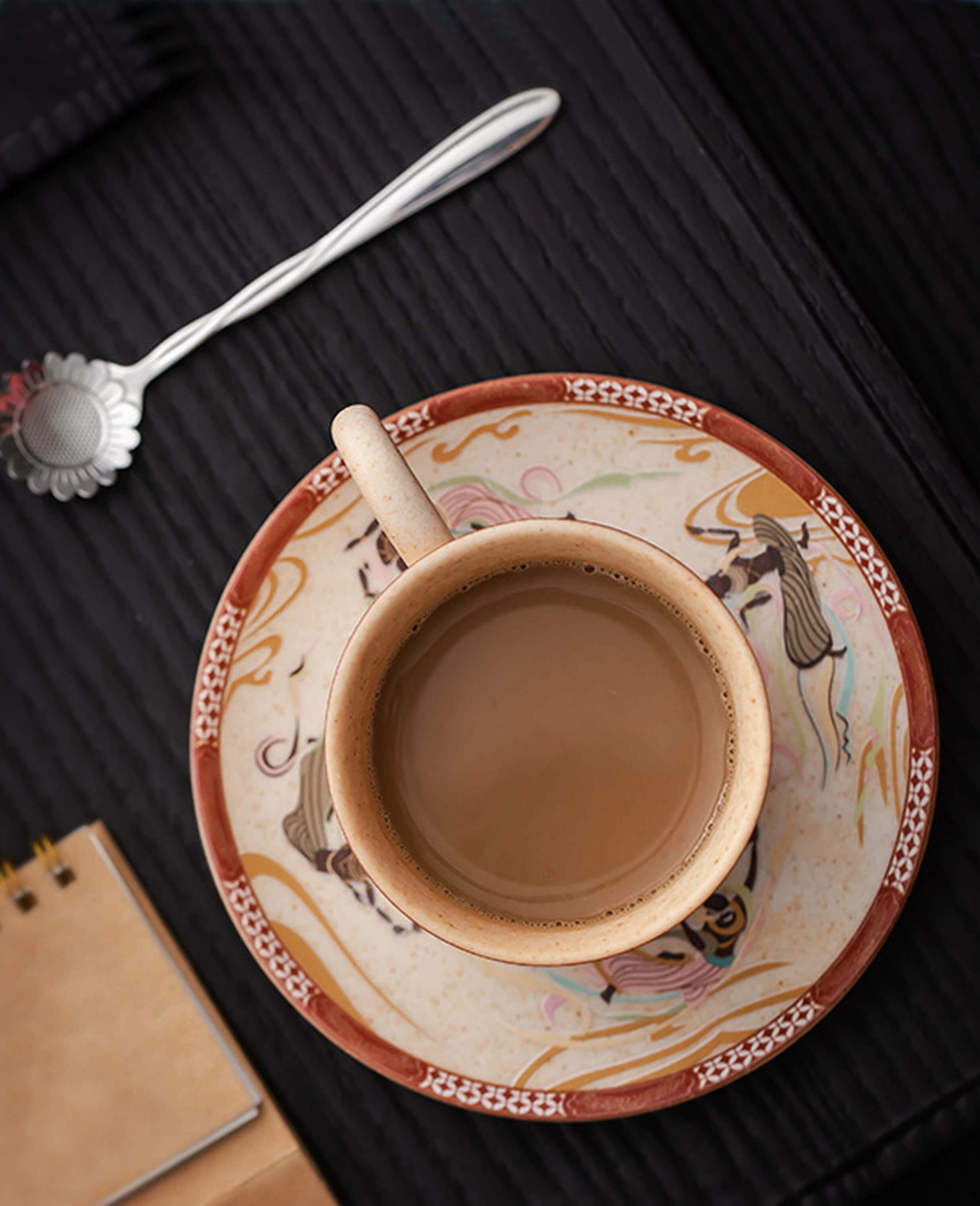 top-down view of ceramic cup and saucer with flying apsara artwork