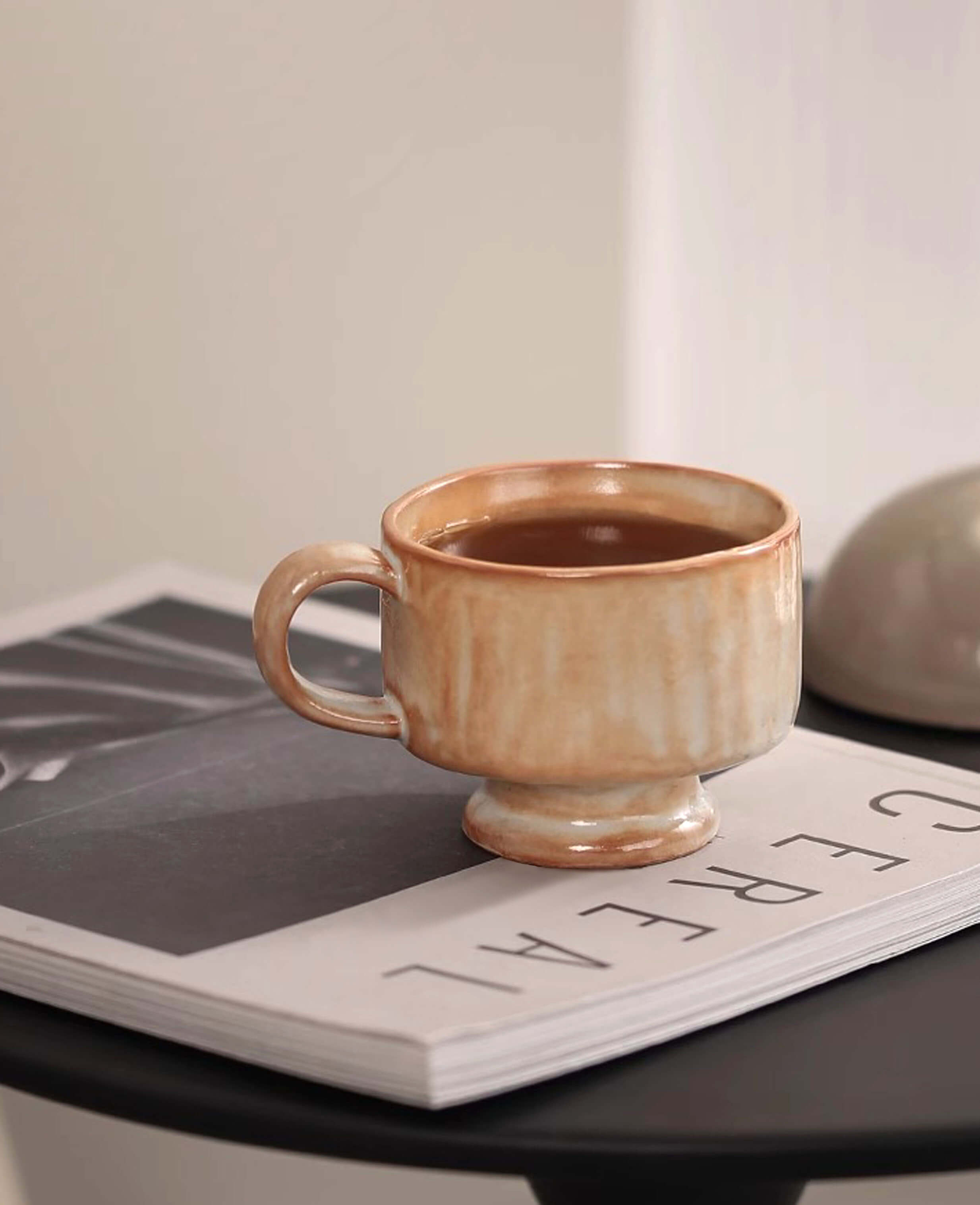 dawn chalice handmade ceramic coffee and tea cup on magazine with minimalist home decor in warm terracotta glaze