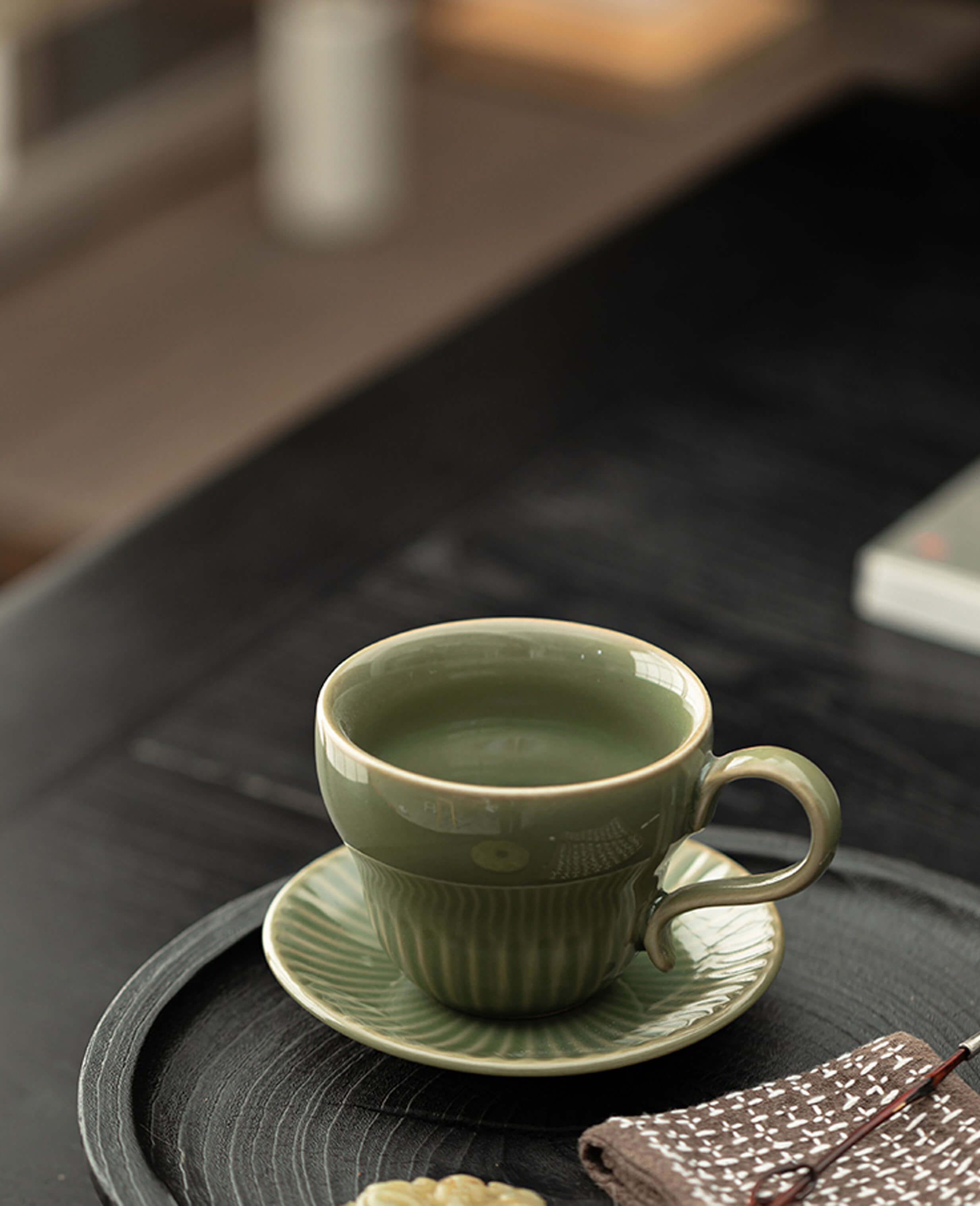 greenstill crest porcelain coffee cup with saucer placed on tray with cookies and cloth