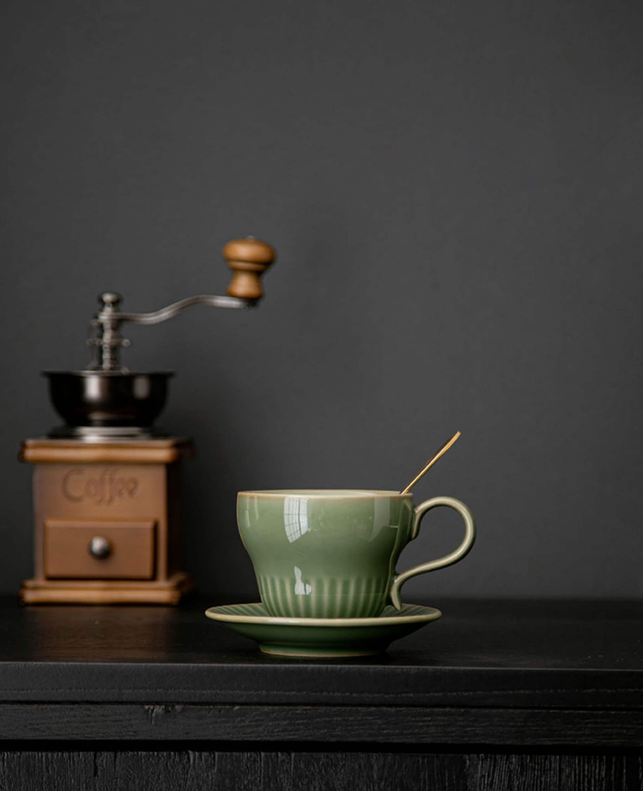 greenstill crest porcelain coffee cup on black table with vintage coffee grinder