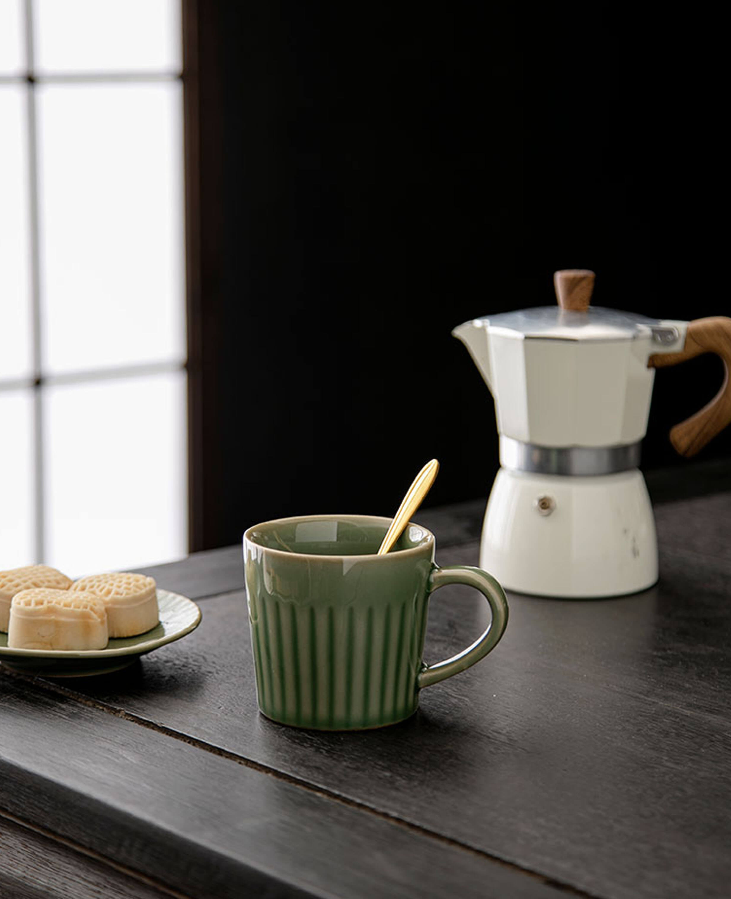 greenstill whisper coffee mug with fluted design beside moka pot and pastry plate in natural light