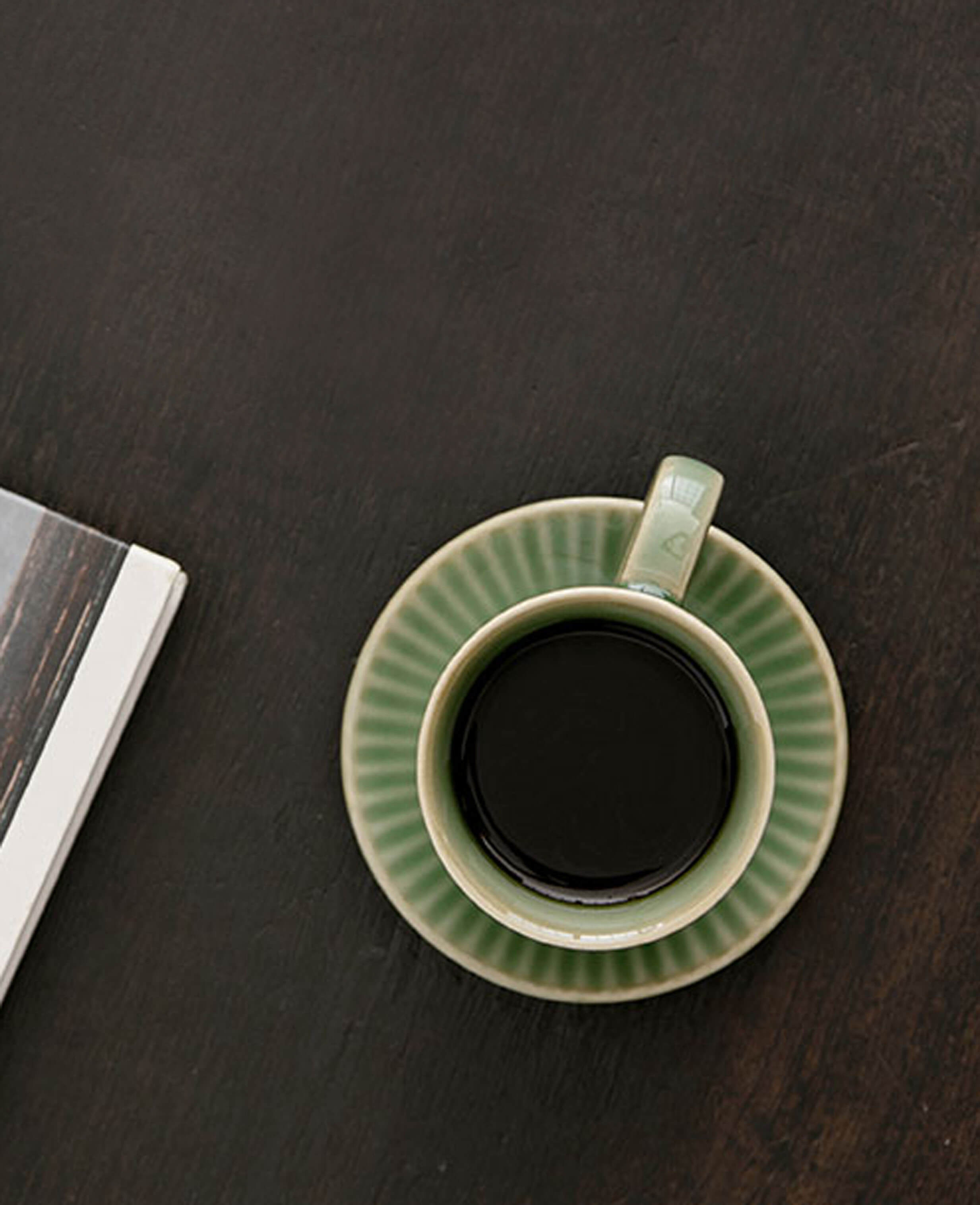 top view of greenstill whisper porcelain coffee mug with dark roast on matching saucer