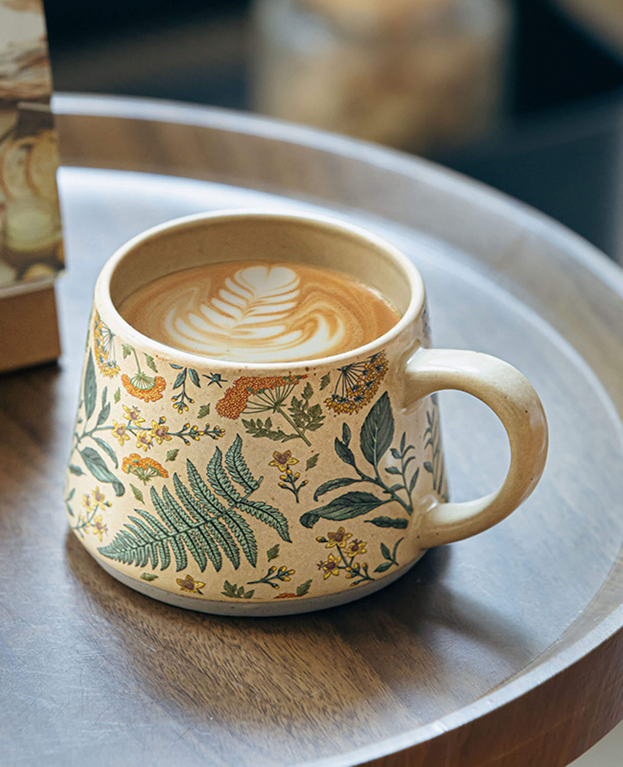 july note ceramic coffee mug with botanical floral print and latte art placed on a wooden tray in natural light