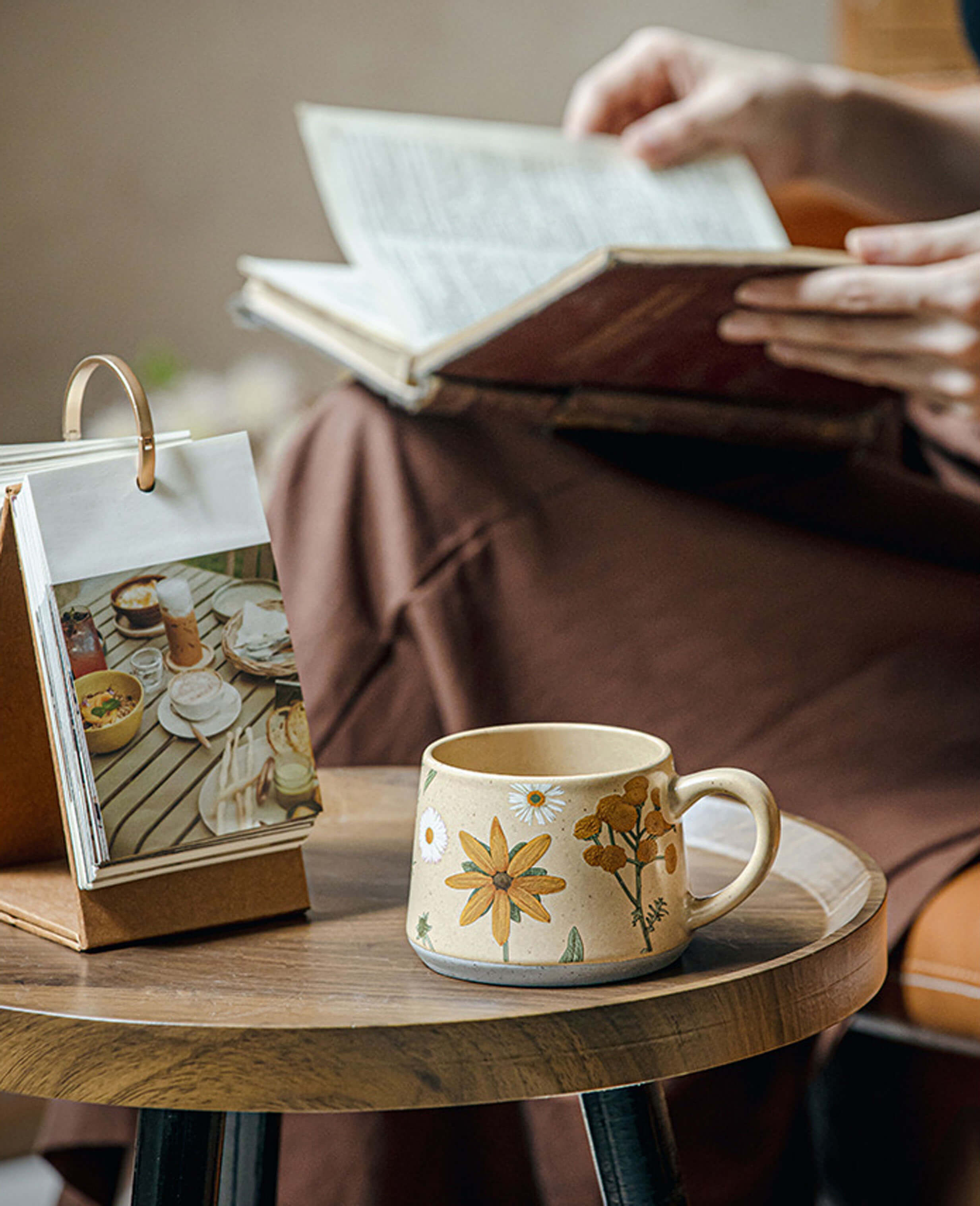 june whisper stoneware coffee mug with daisy and tansy design on wooden table book reading scene summer home setting