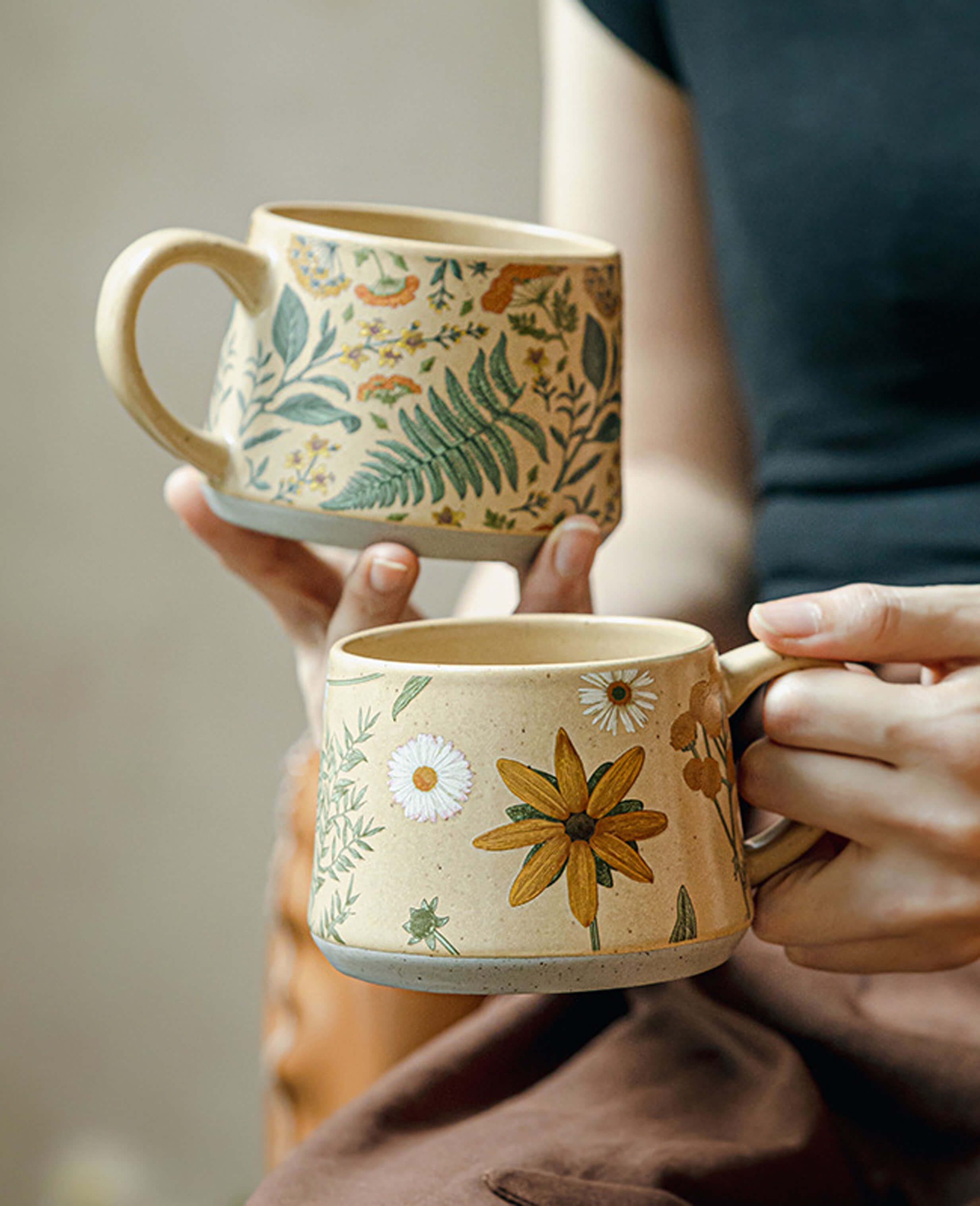 set of summer floral handcrafted stoneware coffee mugs june whisper and july note held in hand