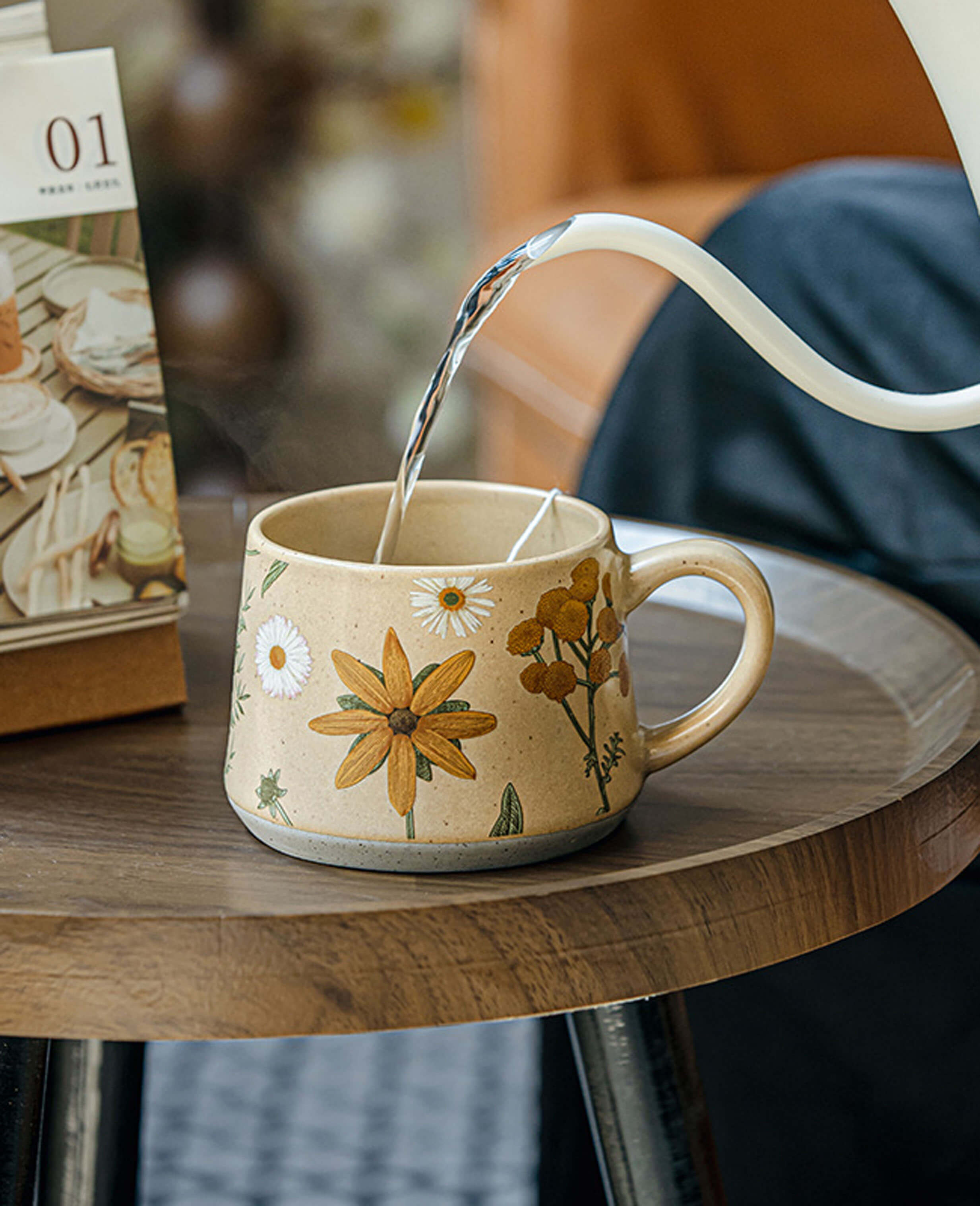 june whisper stoneware tea mug being filled with hot water with daisy and yellow flower illustration from summer imprint collection