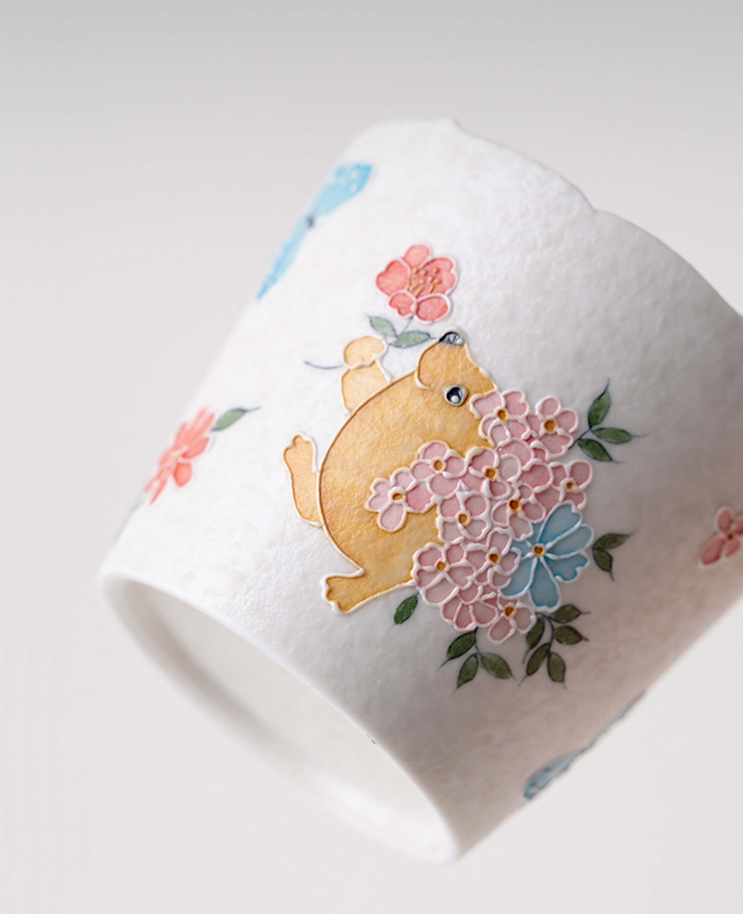 side angle of kindred waltz whimsical ceramic cup featuring floral patterns and friendly hedgehog motif