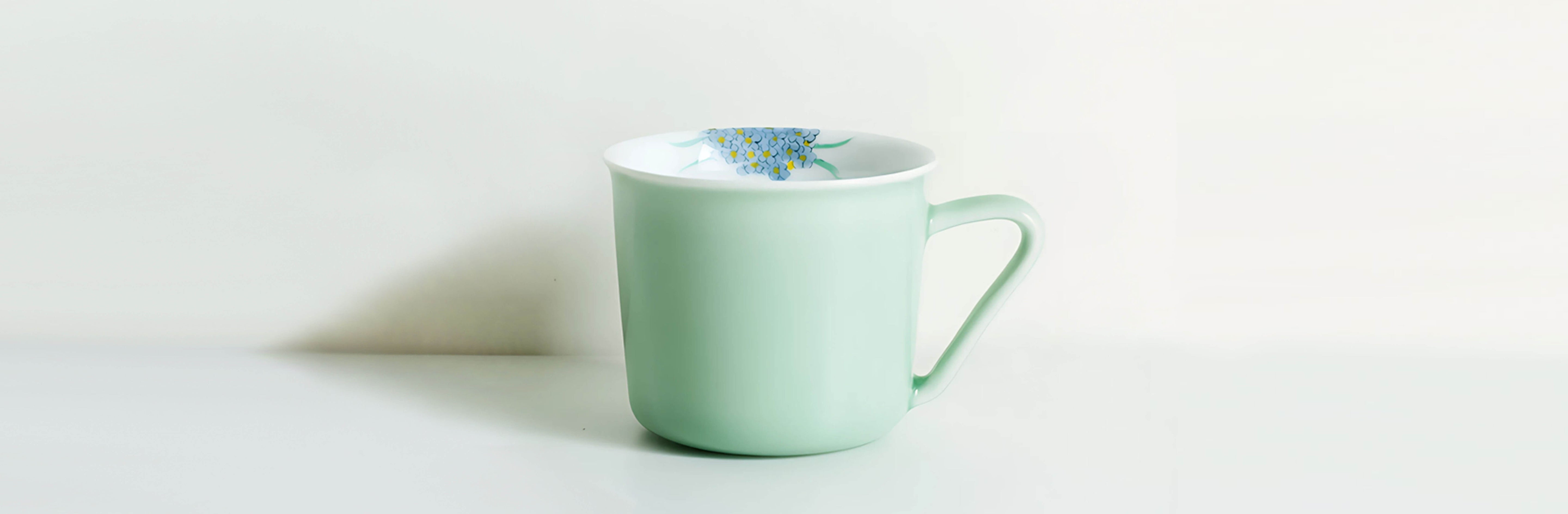 minted memory porcelain coffee and tea cup with hand painted blue flowers and soft green glaze from the painted diary collection on white background