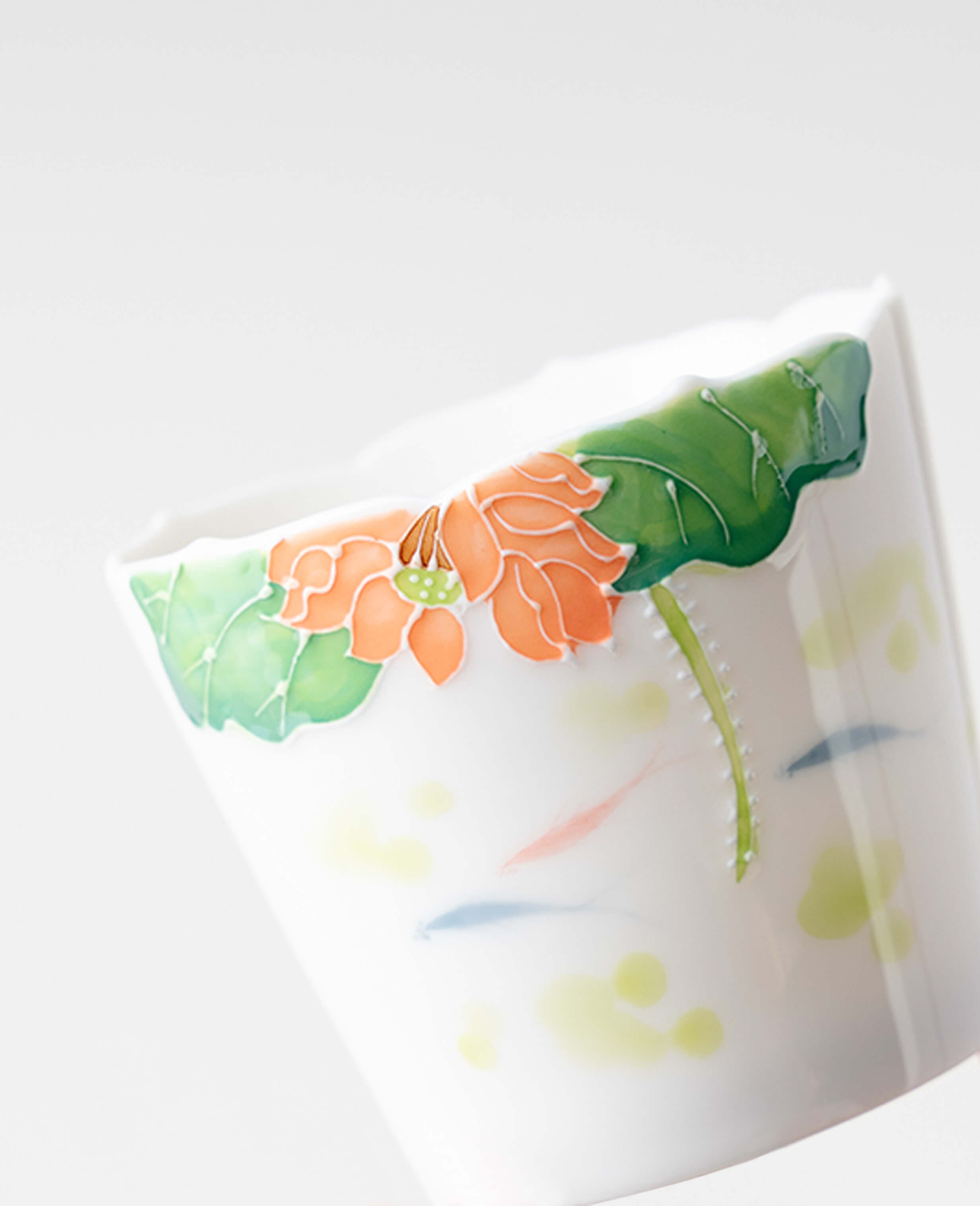 close up of porcelain coffee and tea cup with hand painted lotus flower and subtle fish patterns under the glaze