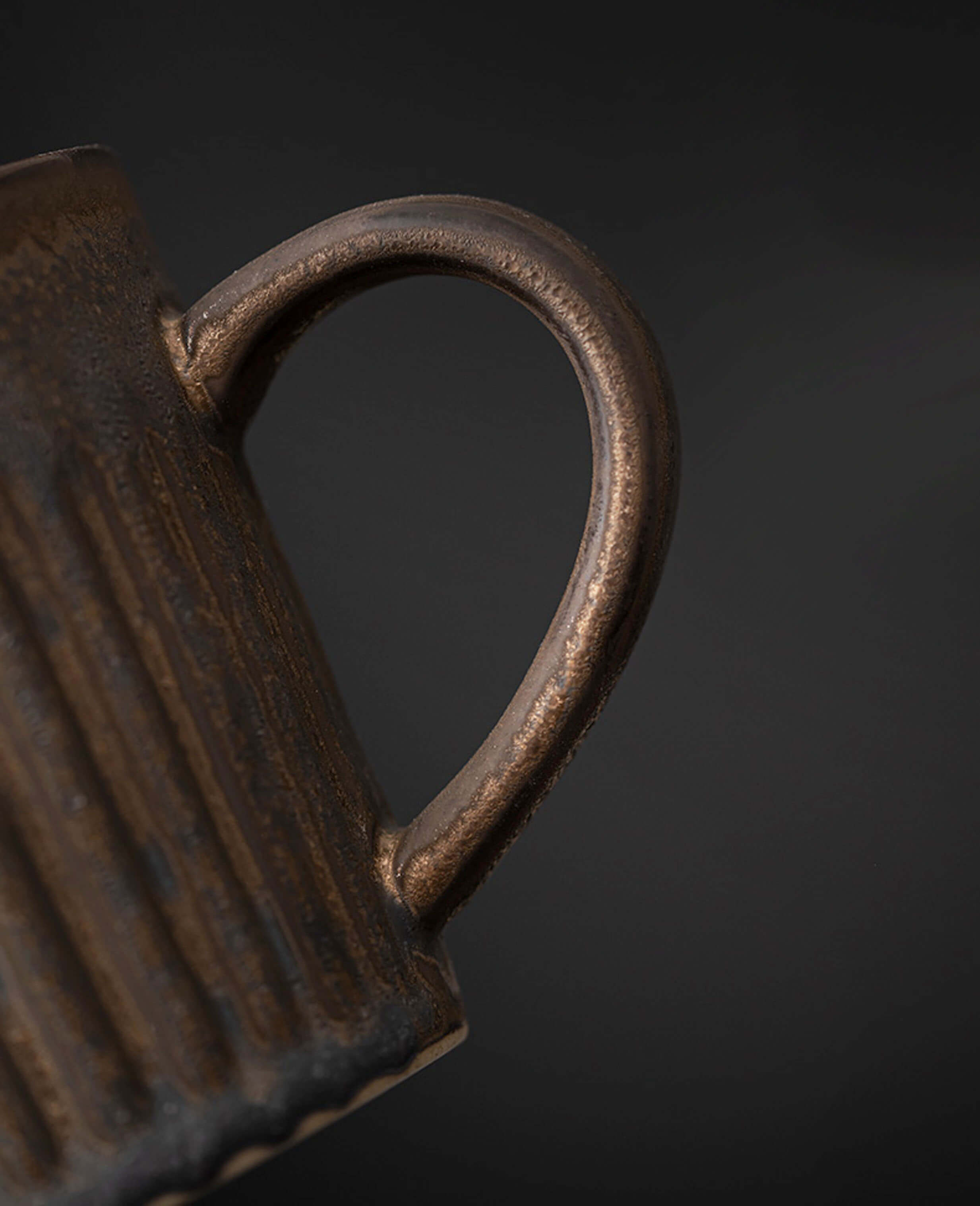close up of rustglow strata handmade ceramic coffee cup handle showing fine detail and textured rusty glaze
