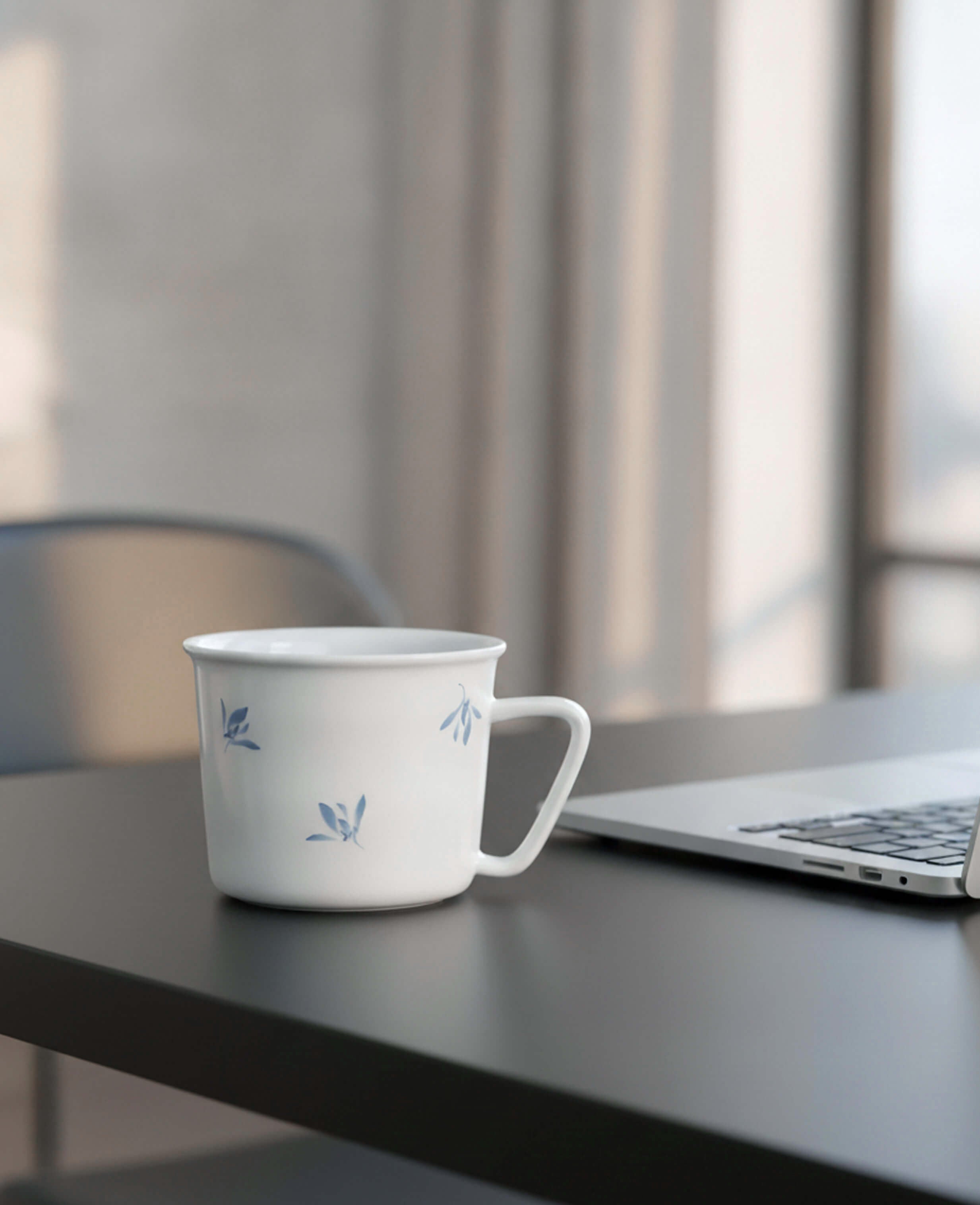 porcelain coffee and tea cup with soft blue leaf motif on black desk beside a laptop from the serene drift painted diary collection