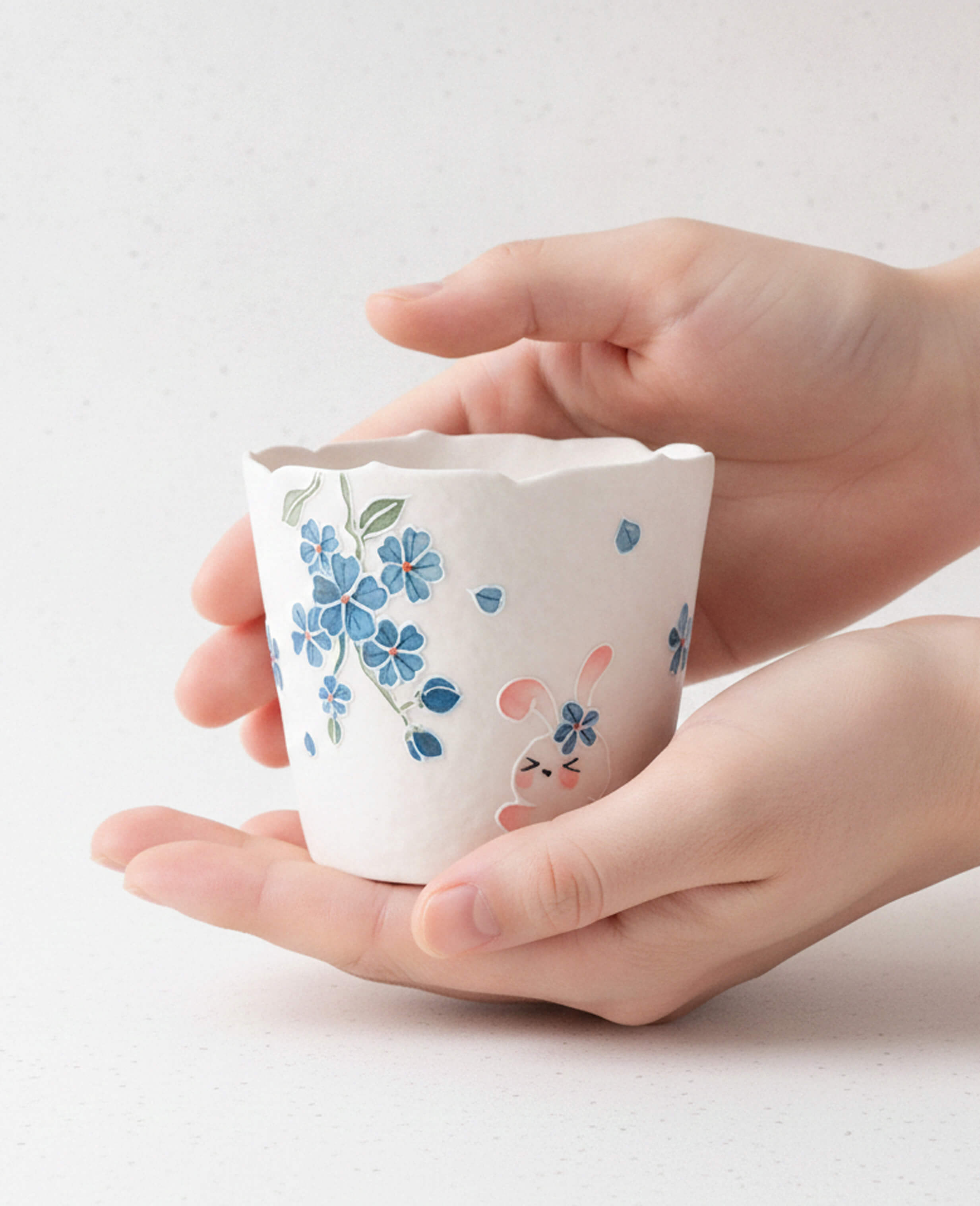 spring reunion handcrafted ceramic coffee and tea cup with cute bunny and flowers pattern held in hand for display