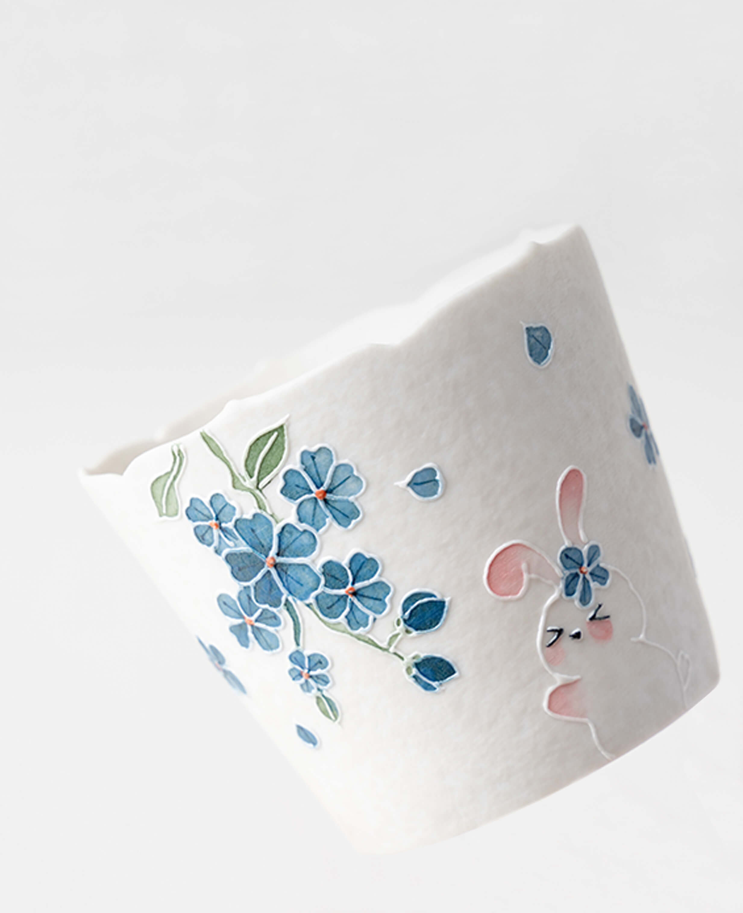 spring reunion ceramic espresso cup side view showing hand painted bunny and falling blue blossoms