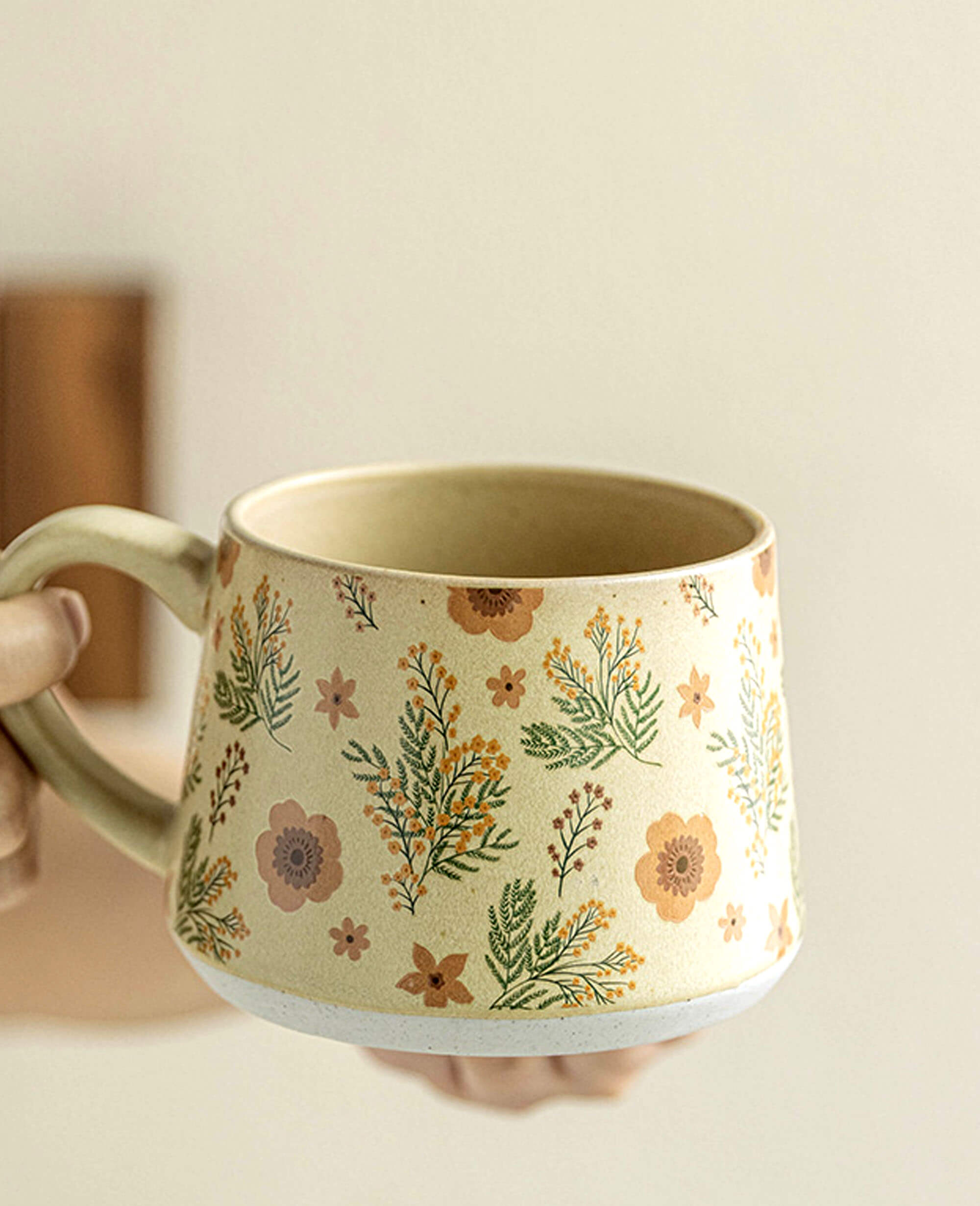 closeup of handcrafted ceramic coffee and tea mug held in hand floral pattern artisan gift idea