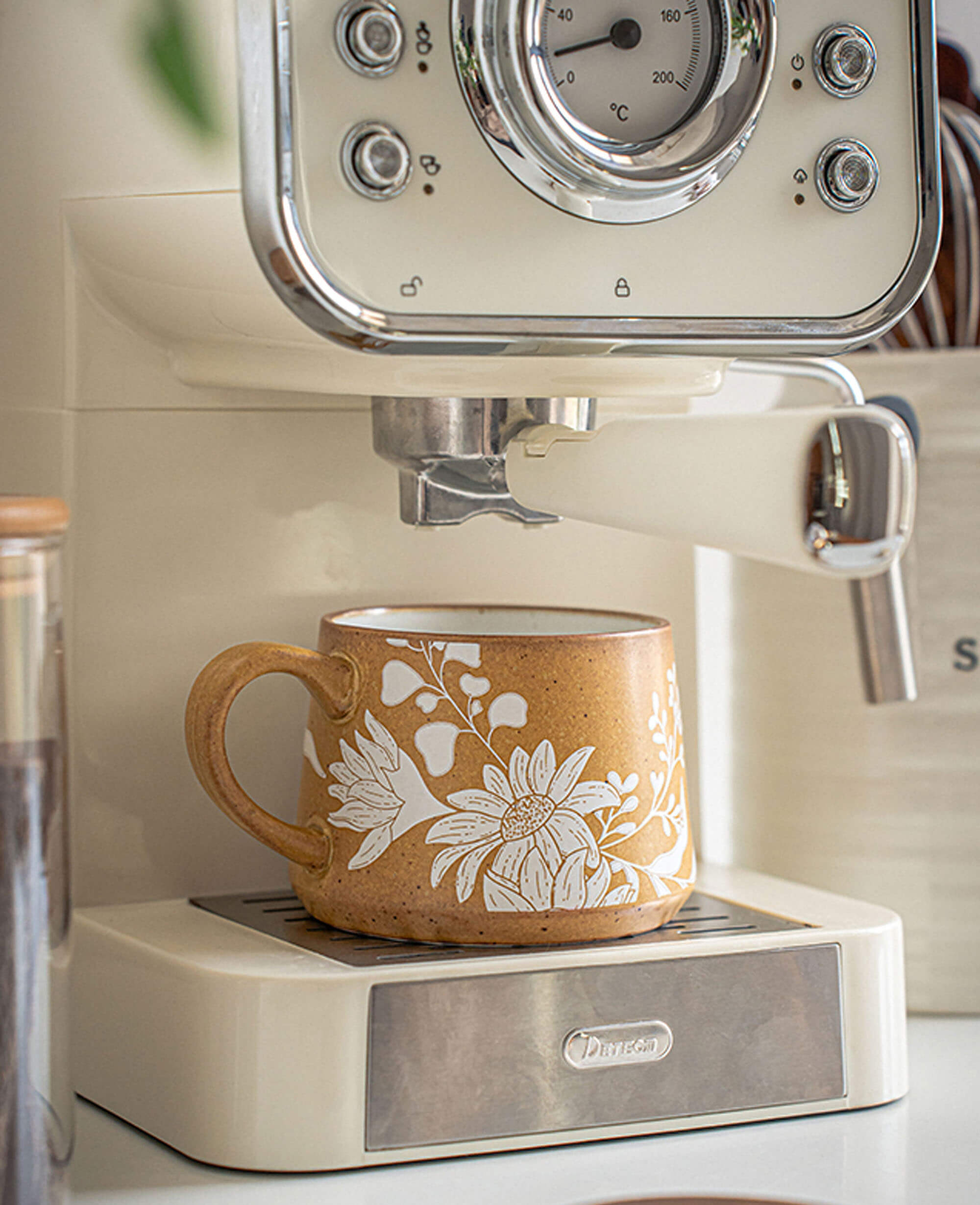 white floral engraved ceramic mug sitting on vintage style espresso machine rustic coffee corner vibe