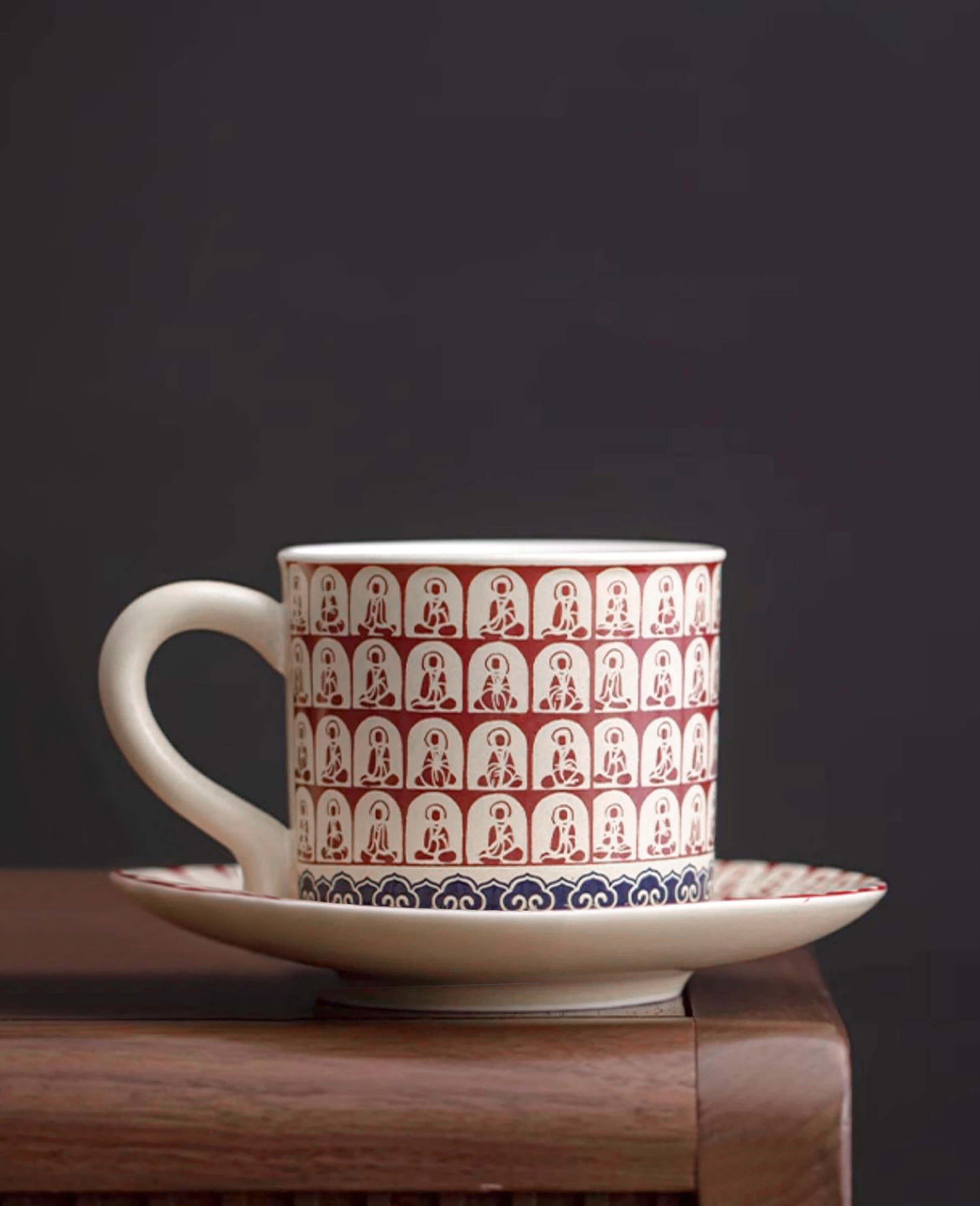 handcrafted ceramic coffee cup and saucer featuring thousand buddhas crimson motif displayed on wooden table