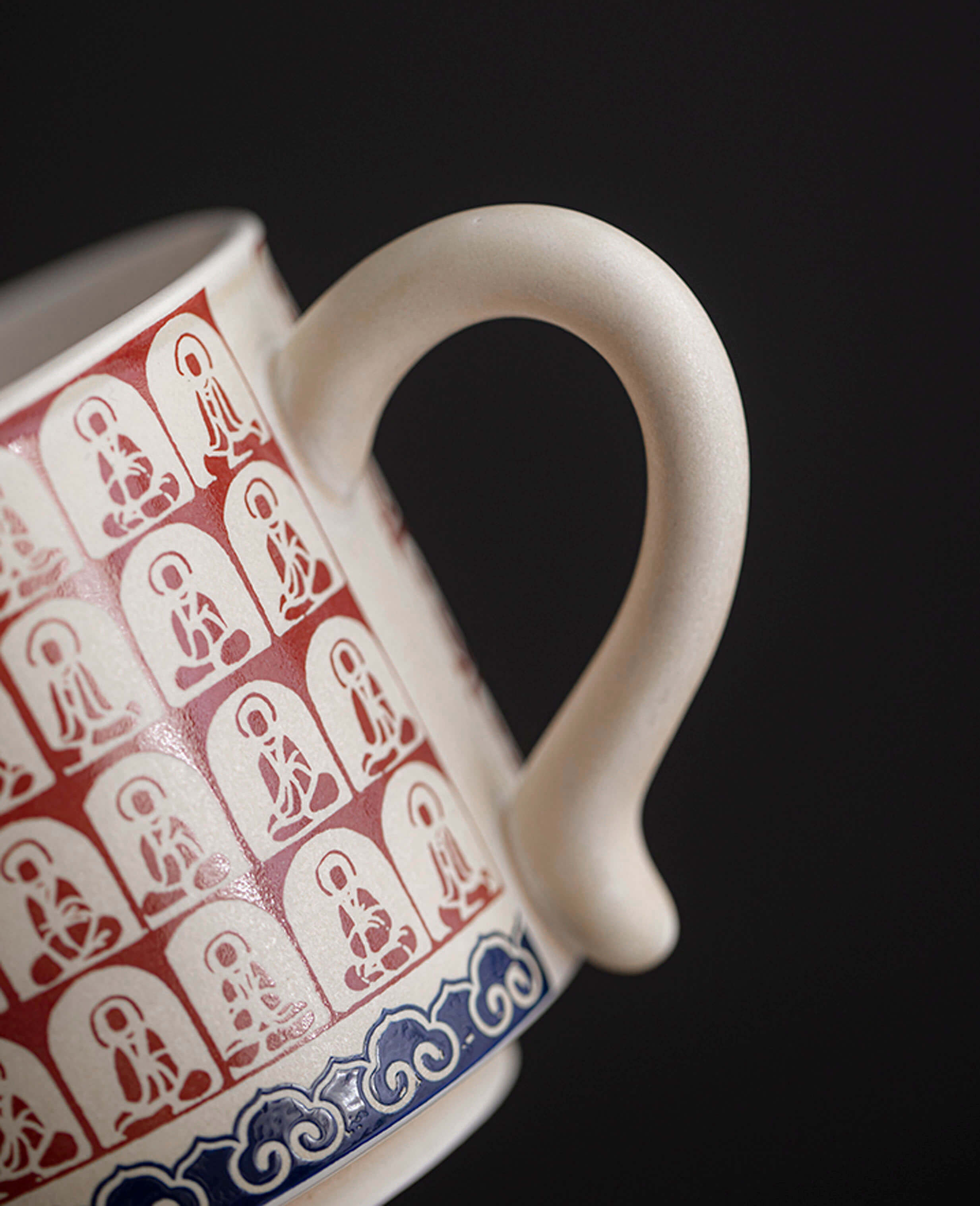 close up of ceramic cup handle with red thousand buddhas pattern and fine blue cloud detailing