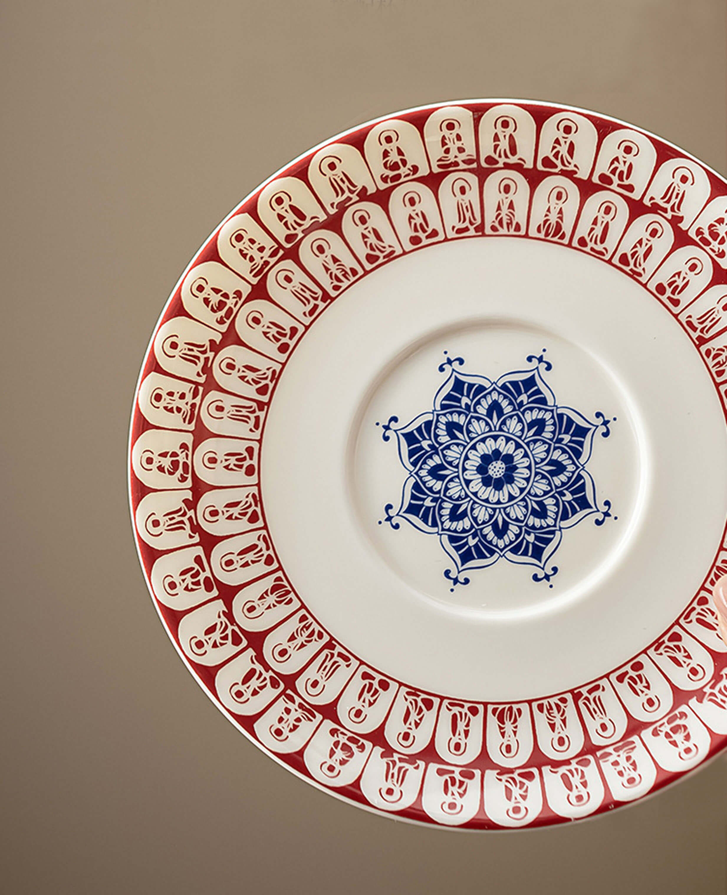 ceramic saucer with red buddha illustrations and intricate central blue mandala