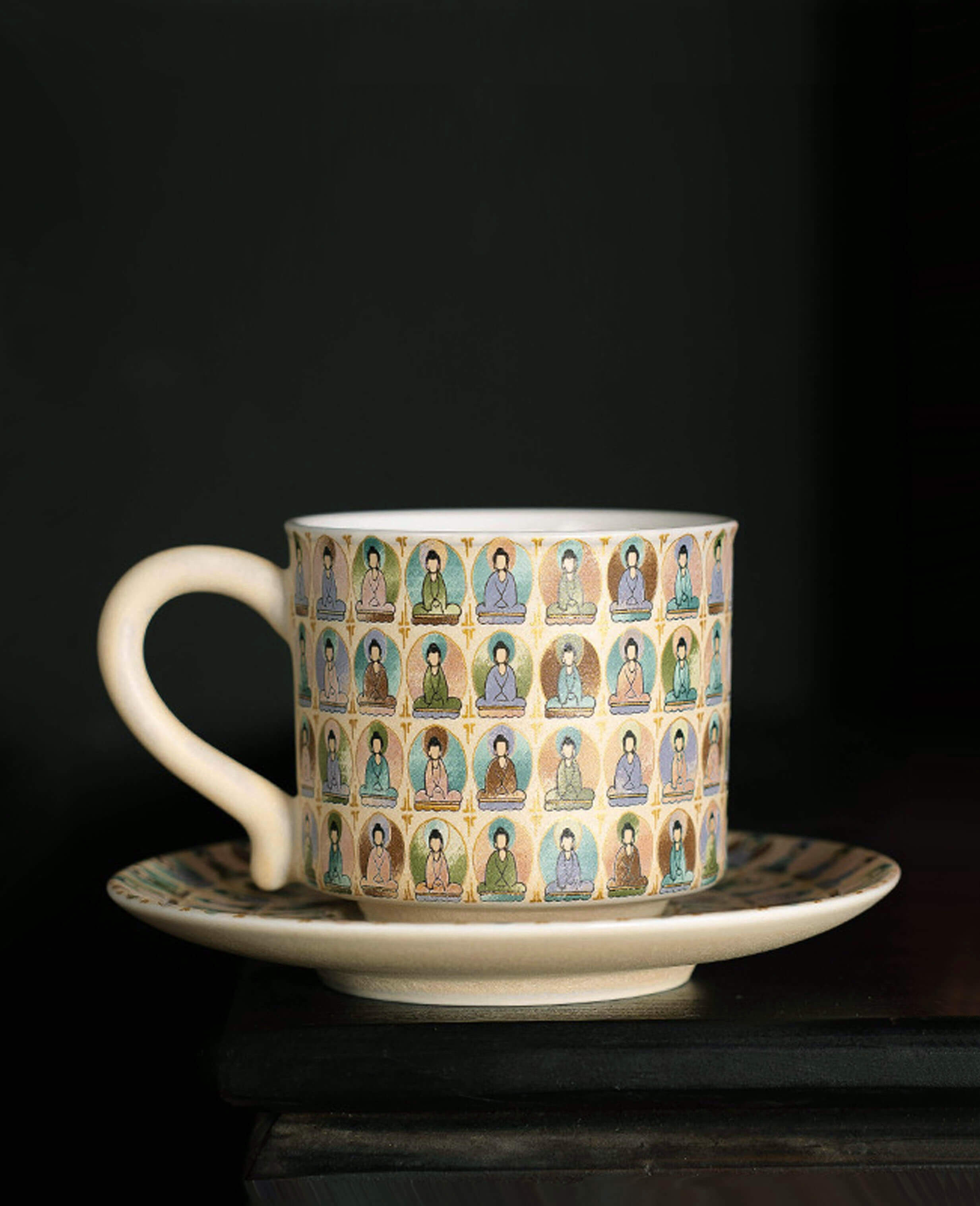 front view of ceramic cup and saucer with pastel thousand buddhas artwork arranged in radial pattern