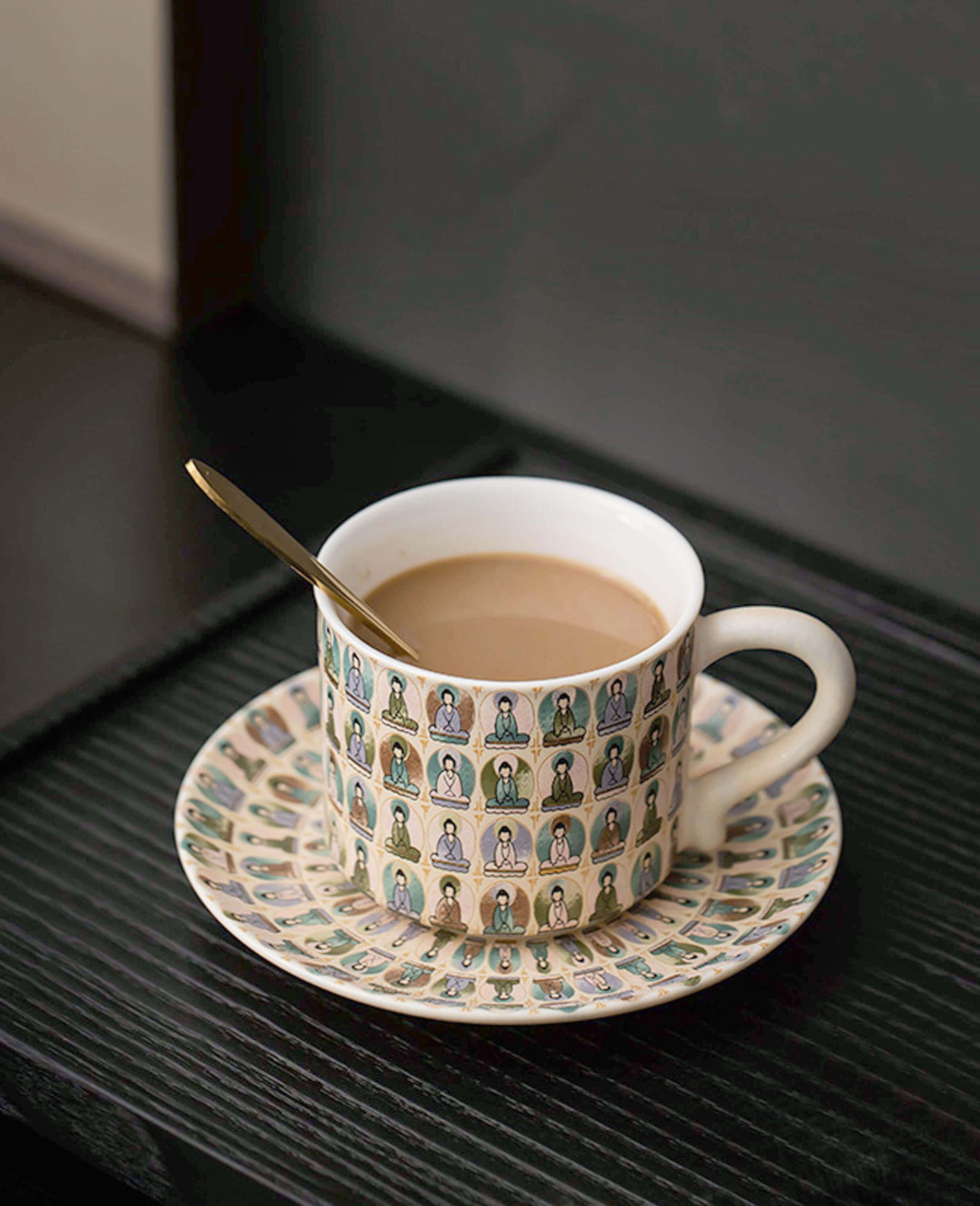 handcrafted ceramic coffee cup and saucer set with colourful thousand buddhas pattern on dark wood table