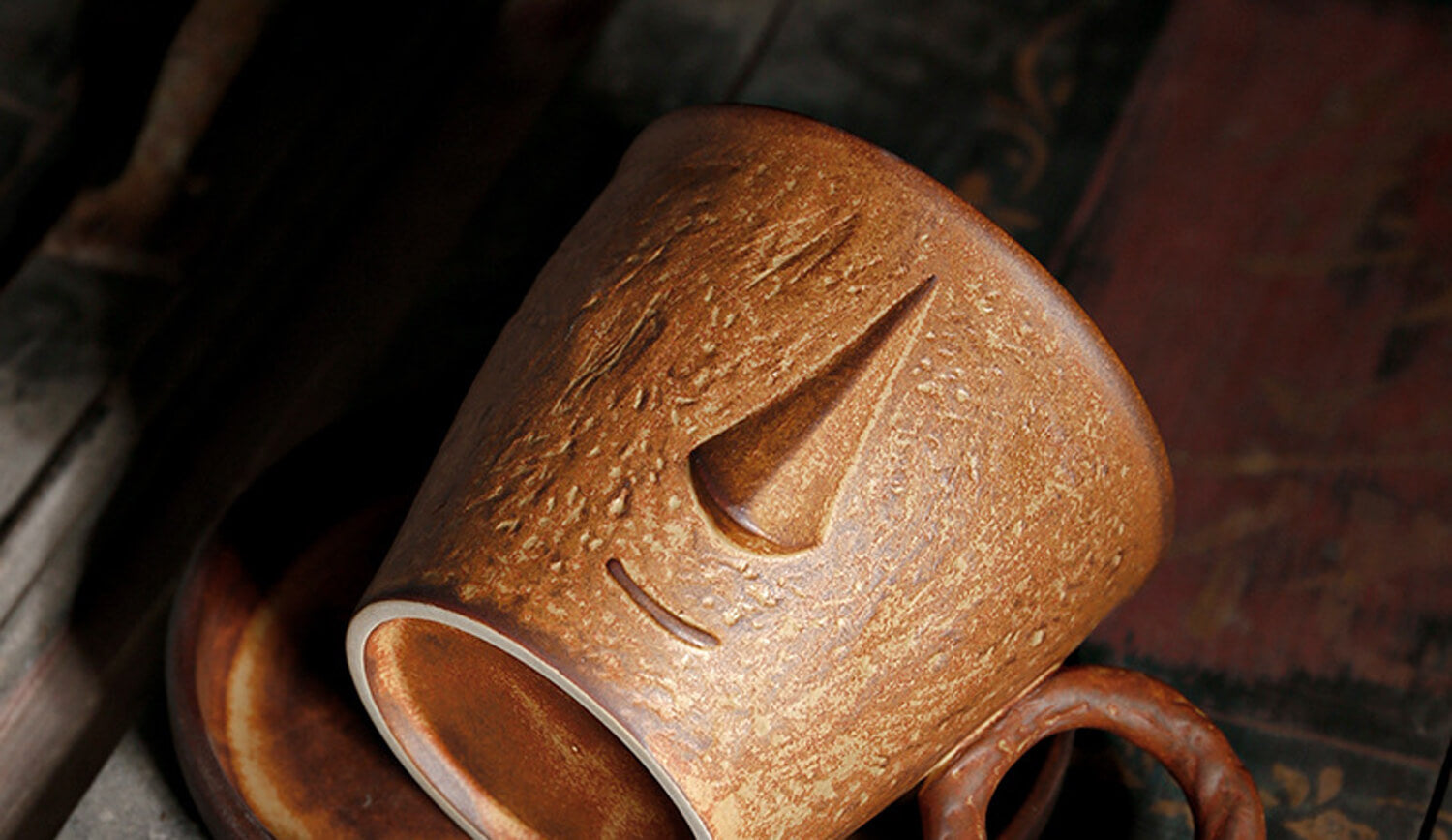 close-up of the toffee glaze muse ceramic coffee cup showcasing the carved symbolic motif and earthy texture