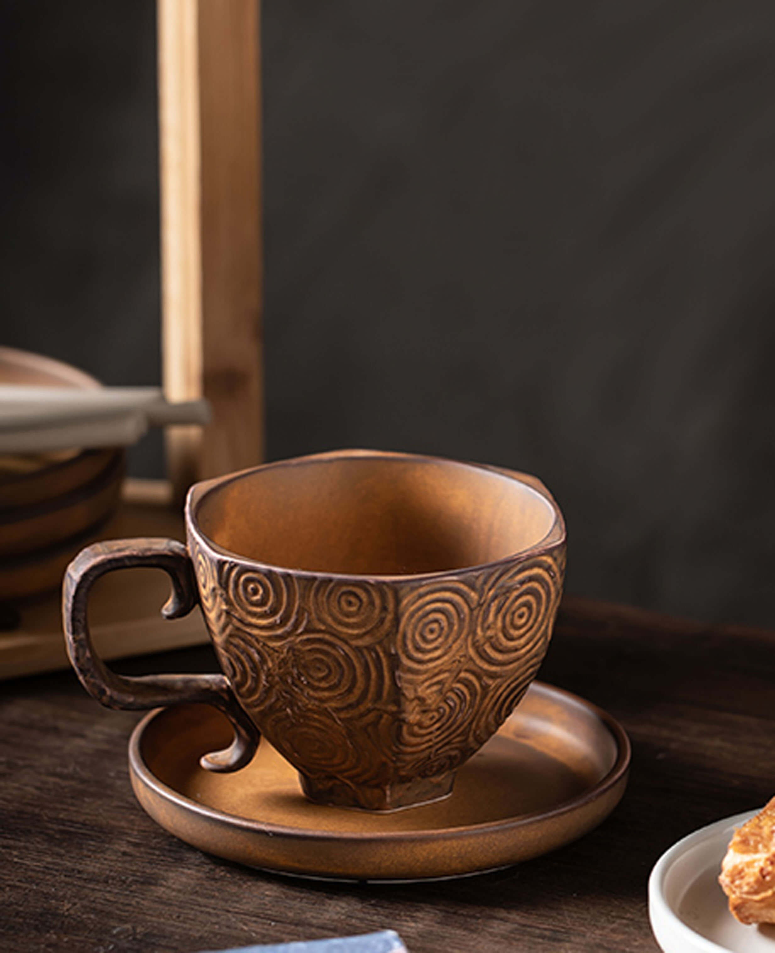 toffee reverie mirage ceramic coffee cup on matching saucer, shown from side view on a wooden table